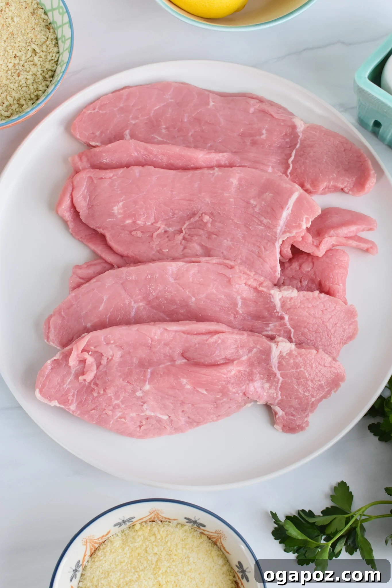 Easy Veal Milanese Recipe showing breaded veal on a plate ready for frying.