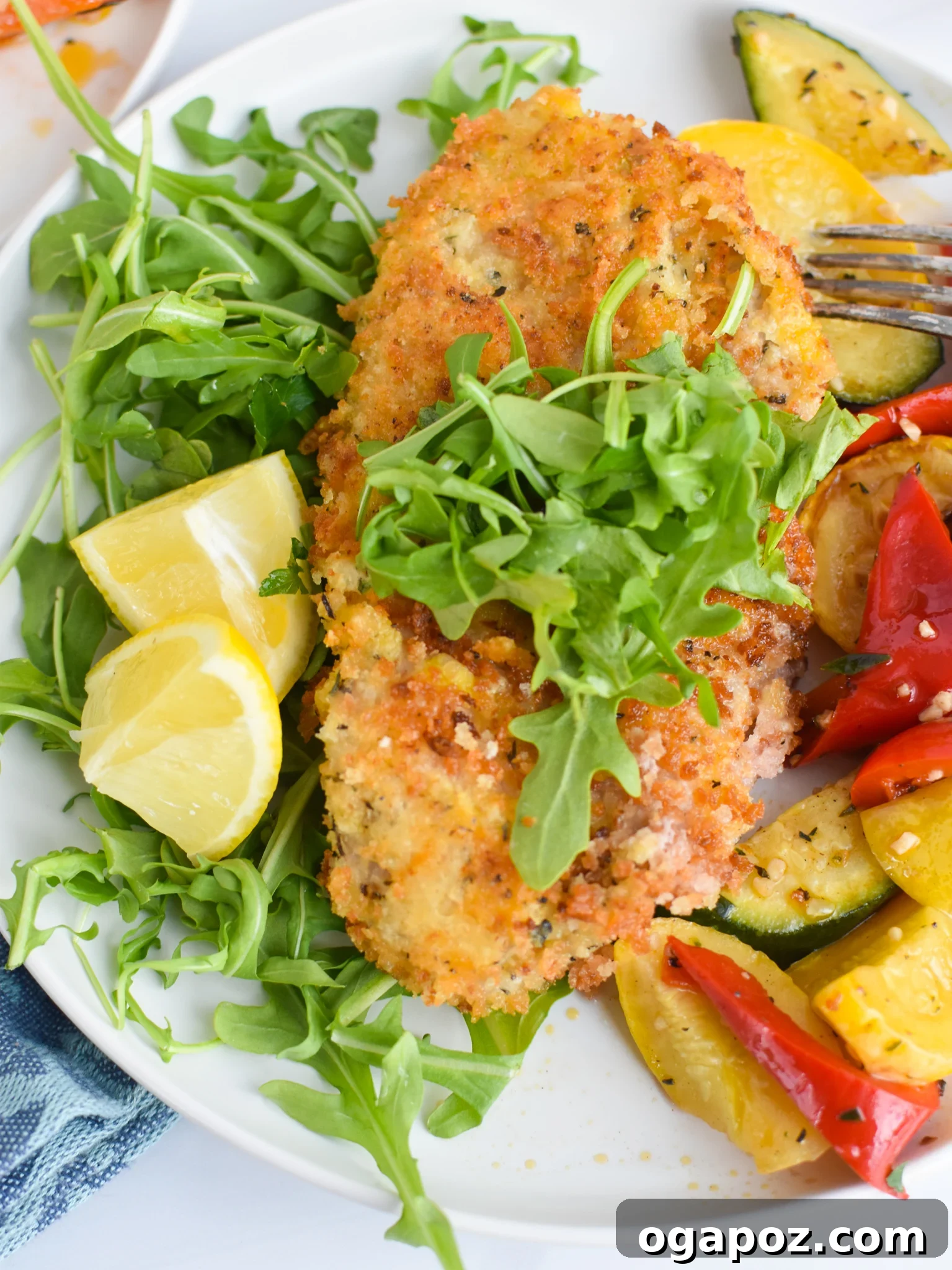 Easy Veal Milanese Recipe served with lemon wedges and arugula.