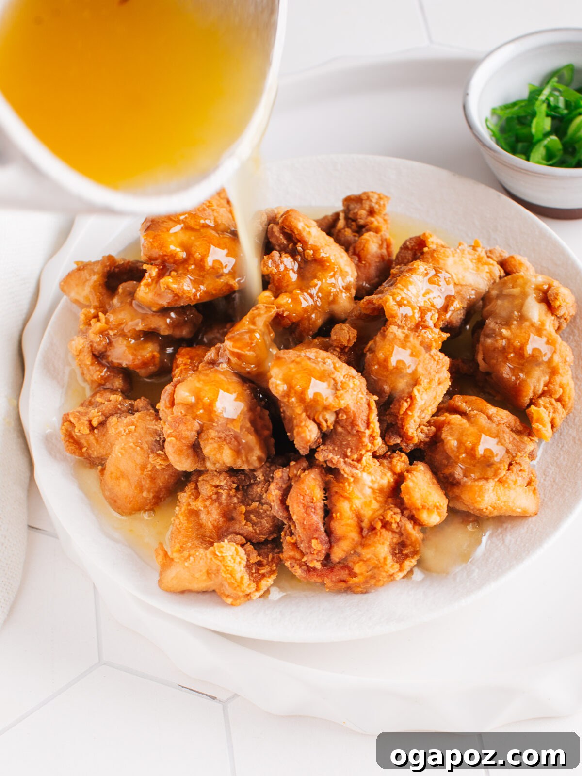 Better Than Takeout Lemon Chicken At Home 2 Crispy Lemon Chicken served on a plate, glistening with a vibrant lemon sauce and garnished with fresh green onions.