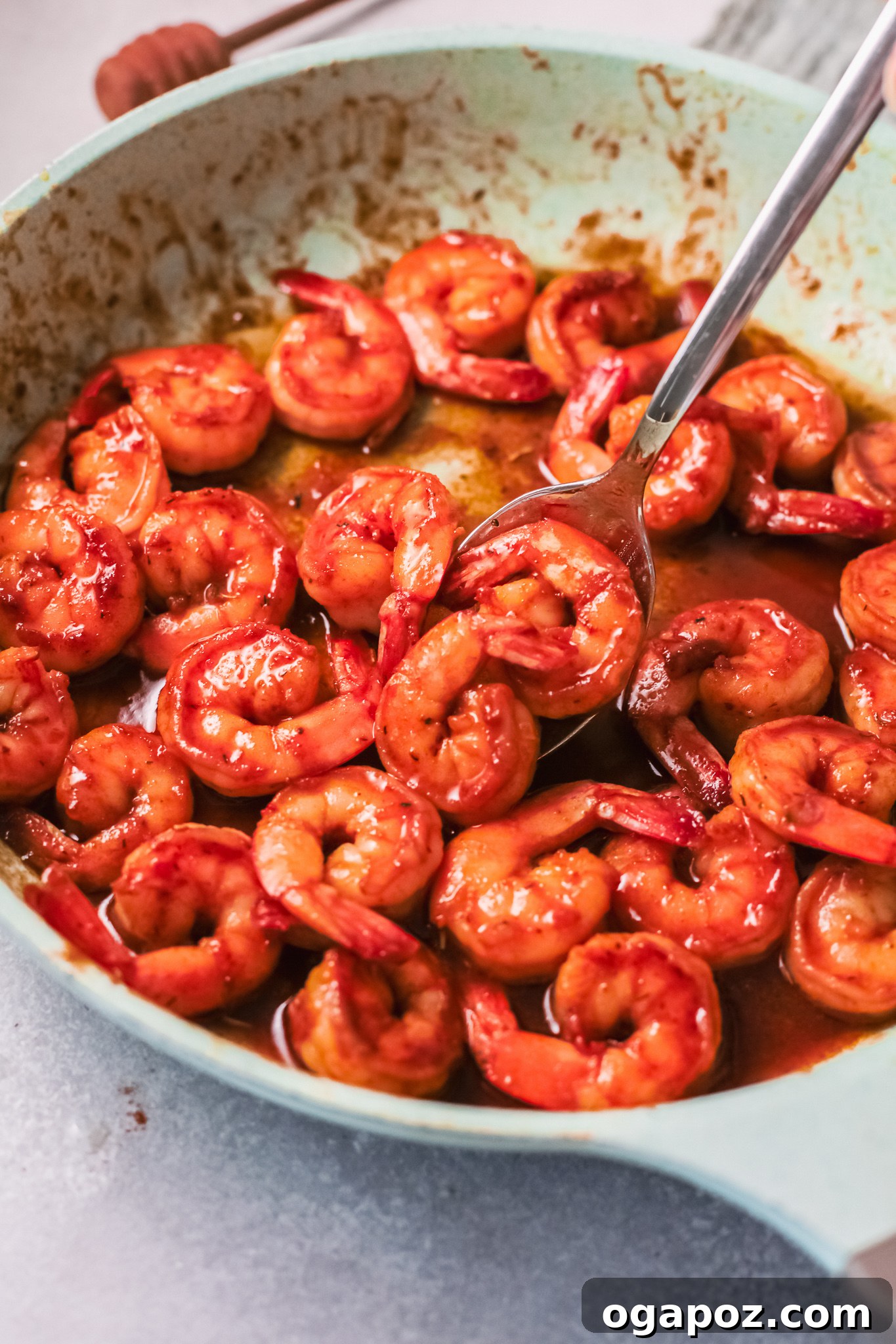 Spicy Southern Shrimp in Minutes 4 Close-up of cooked Cajun shrimp in a rustic bowl, garnished with fresh herbs and a spoon.