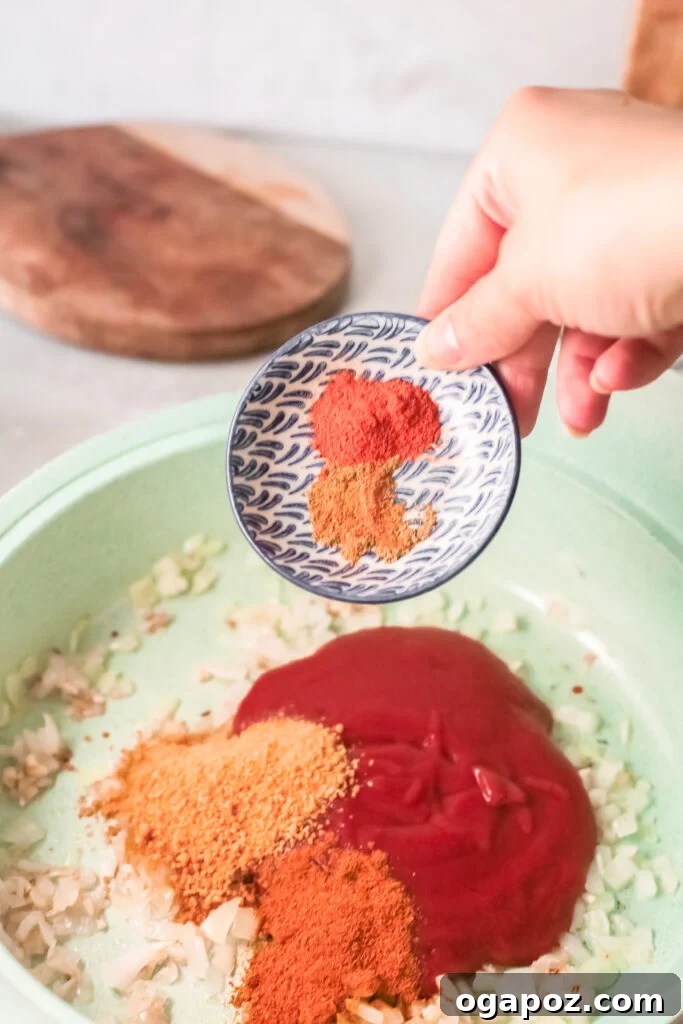 Spiced Red Lentil Curry 6 Tomato sauce and spices like curry powder, garam masala, and cayenne pepper being stirred into the sautéed aromatics in a pan, releasing their rich aromas.