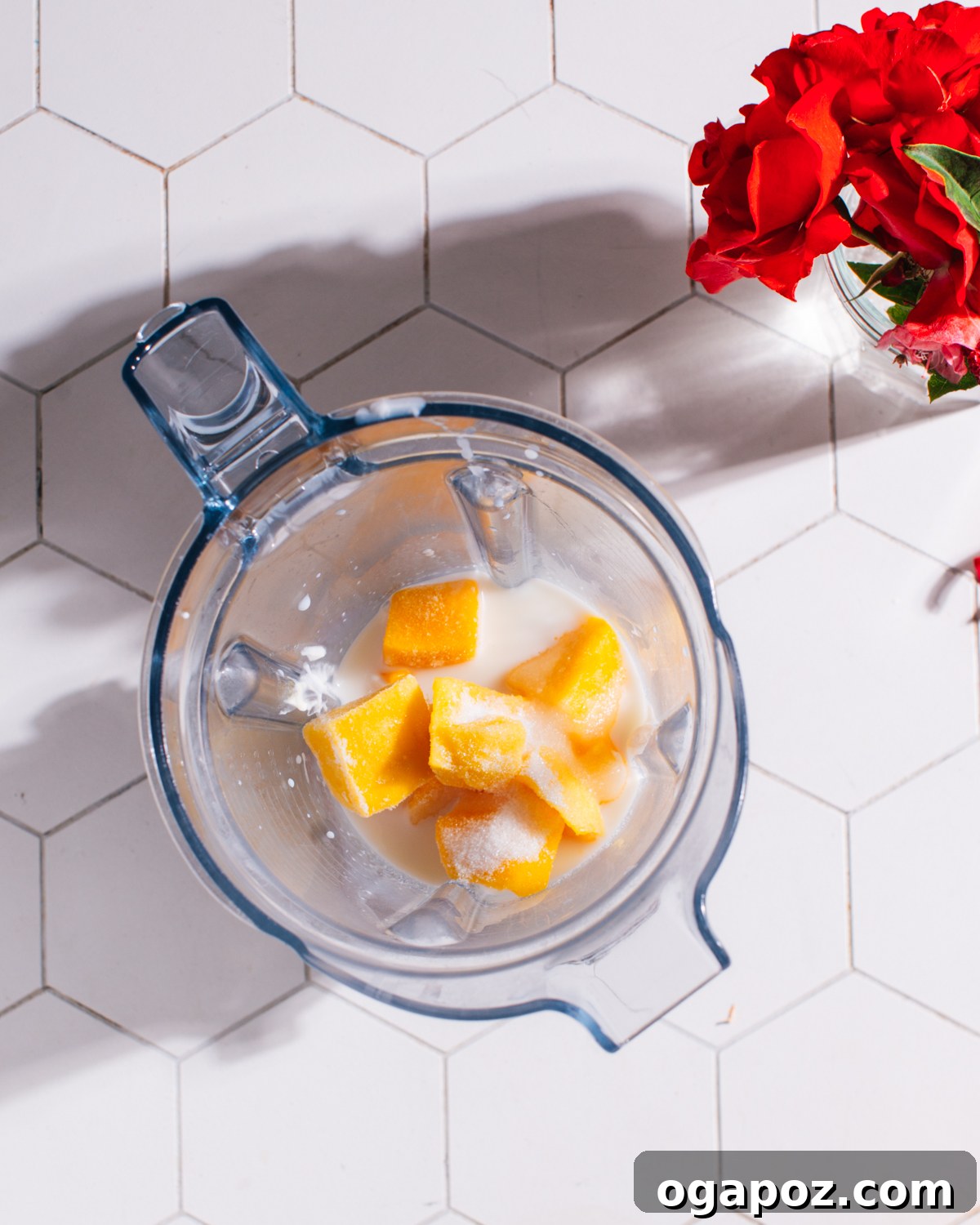 Diced mango, yogurt, and milk in a blender cup before blending for mango lassi.