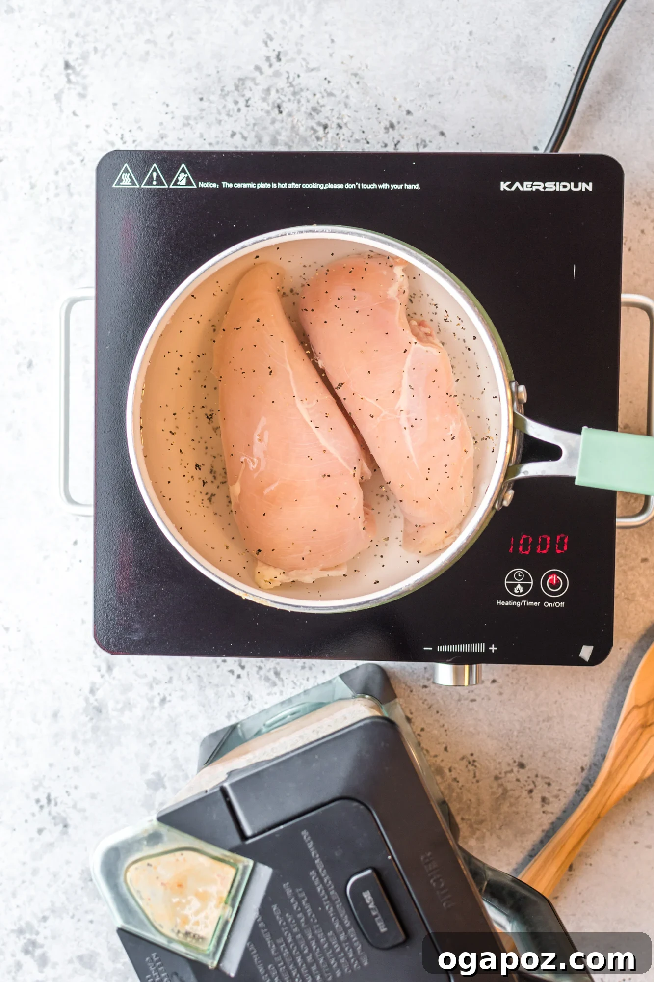 Raw chicken breasts poaching in a saucepan.