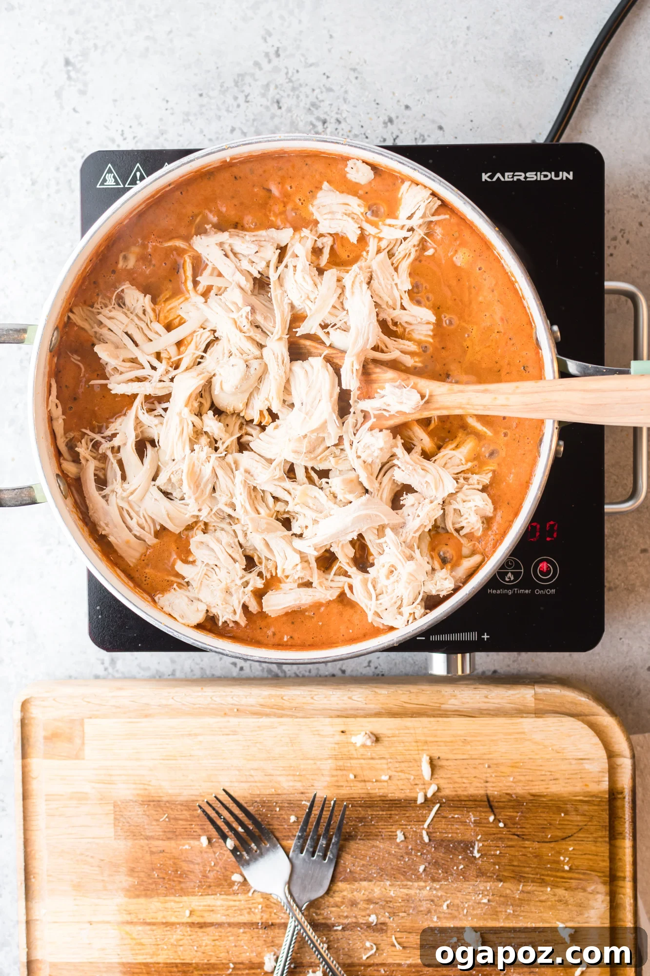 Close-up of shredded chicken simmering in rich tinga sauce.