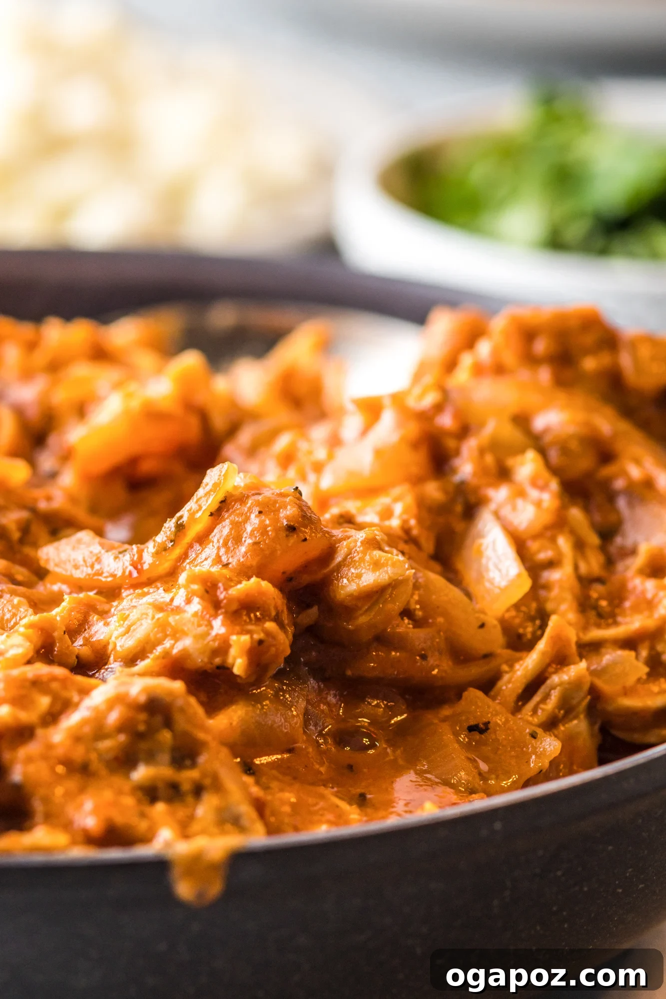 A spoon scooping creamy chicken tinga from a bowl.