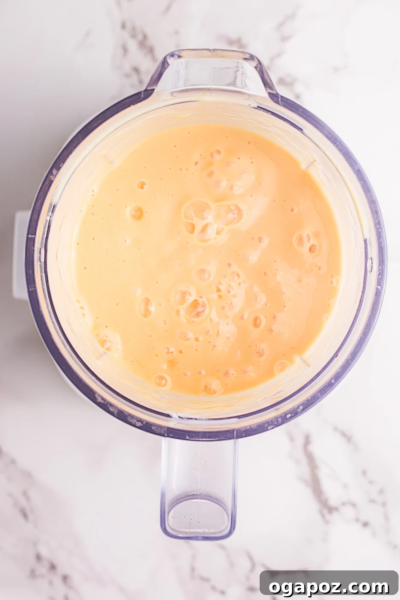 Velvety Mango Lassi 6 Two glasses of freshly prepared Mango Lassi, garnished with slivered almonds, placed next to a blender on a kitchen counter.