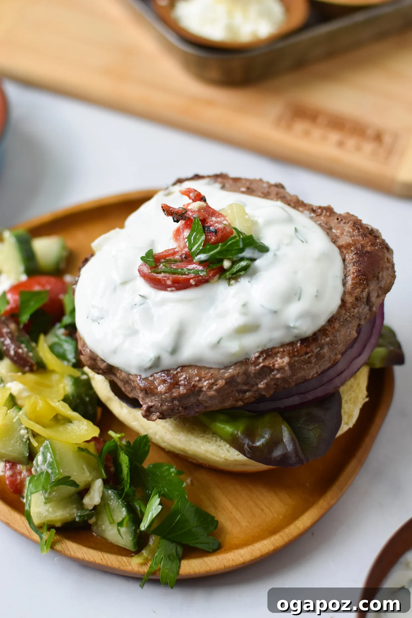 Effortless Greek Burgers 4 Easy Greek Burger Recipe being assembled with tzatziki.