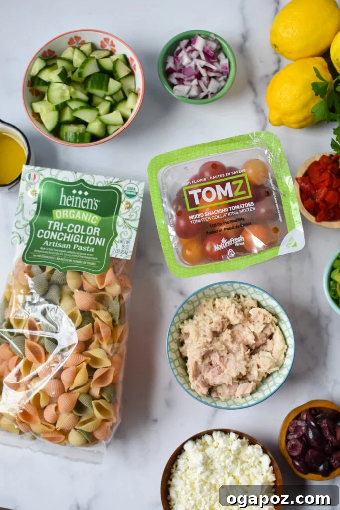 Zesty Mediterranean Tuna Pasta Salad 3 A vibrant selection of fresh ingredients laid out for Mediterranean Tuna Pasta Salad, including cherry tomatoes, cucumbers, olives, tuna cans, pasta, and herbs.