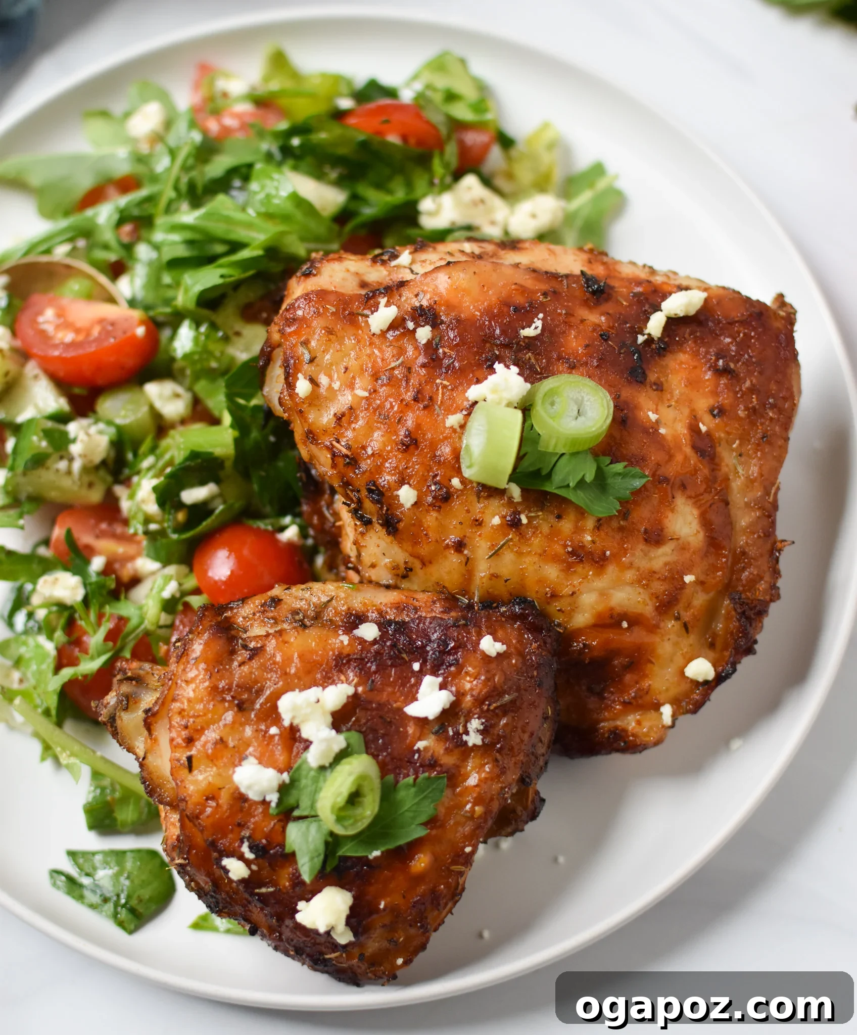 Zesty Mediterranean Air Fryer Chicken Thighs 2 Platter of golden brown Air Fryer Mediterranean Chicken Thighs garnished with fresh parsley and served with a vibrant chopped salad.