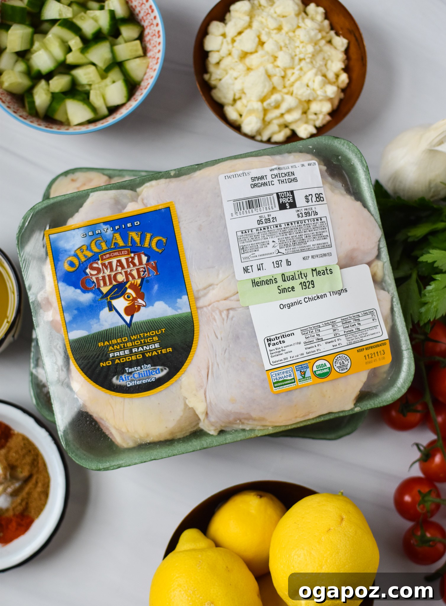 Zesty Mediterranean Air Fryer Chicken Thighs 3 Ingredients for Air Fryer Mediterranean Chicken Thighs laid out on a white surface, including chicken thighs, herbs, spices, lemon, olive oil, and red wine vinegar.