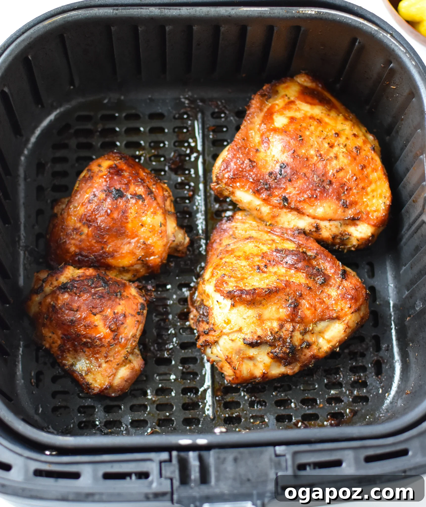 Zesty Mediterranean Air Fryer Chicken Thighs 6 Air Fryer Mediterranean Chicken Thighs cooking inside an air fryer basket, with golden-brown, crispy skin.