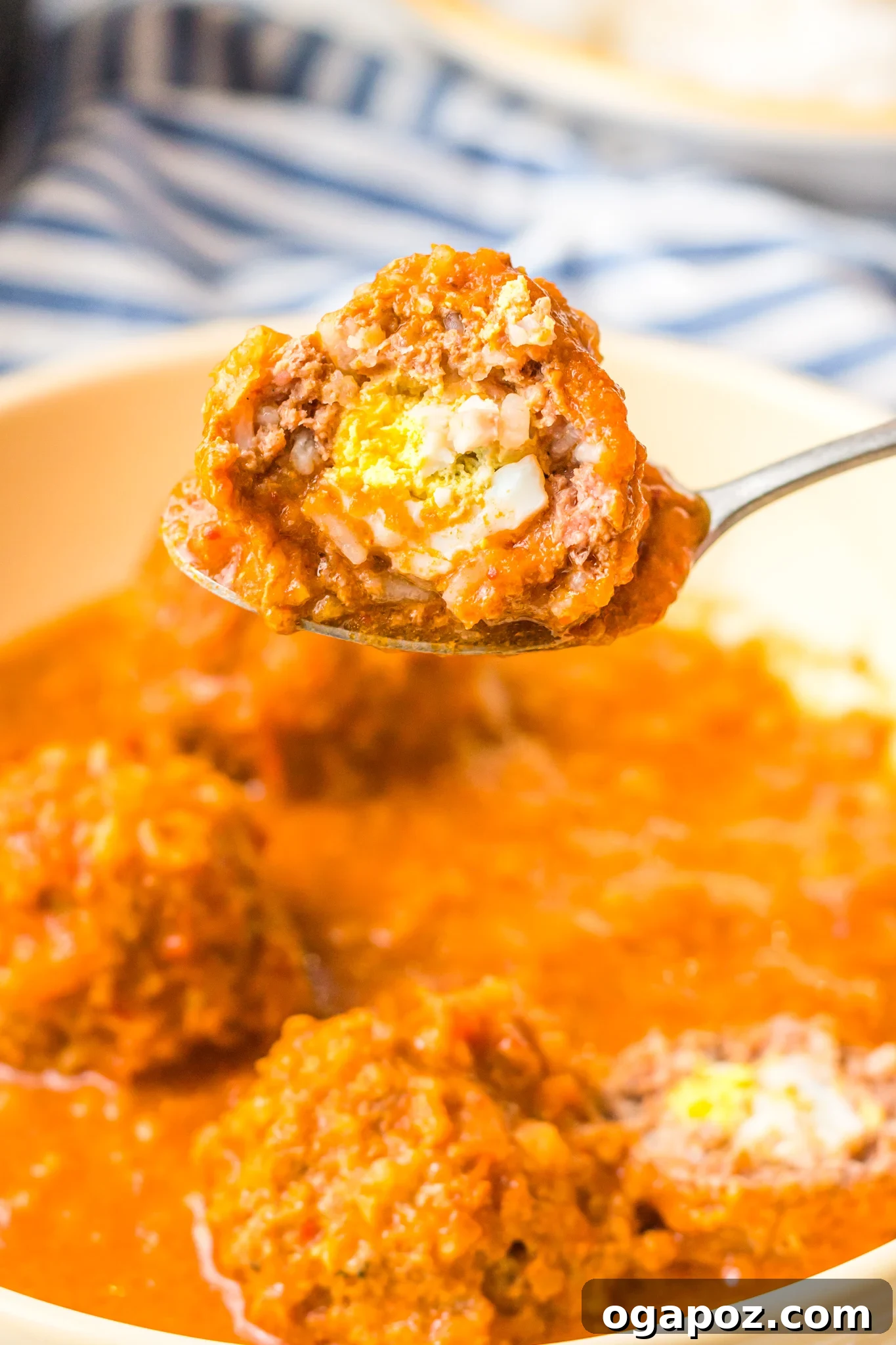 Smoky Chipotle Meatballs 2 A spoon holding a single Albondigas en Chipotle meatball, showing the visible boiled egg inside.