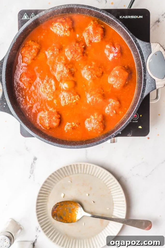 Smoky Chipotle Meatballs 11 Albondigas en Chipotle meatballs simmering gently in the rich red sauce in a pot.