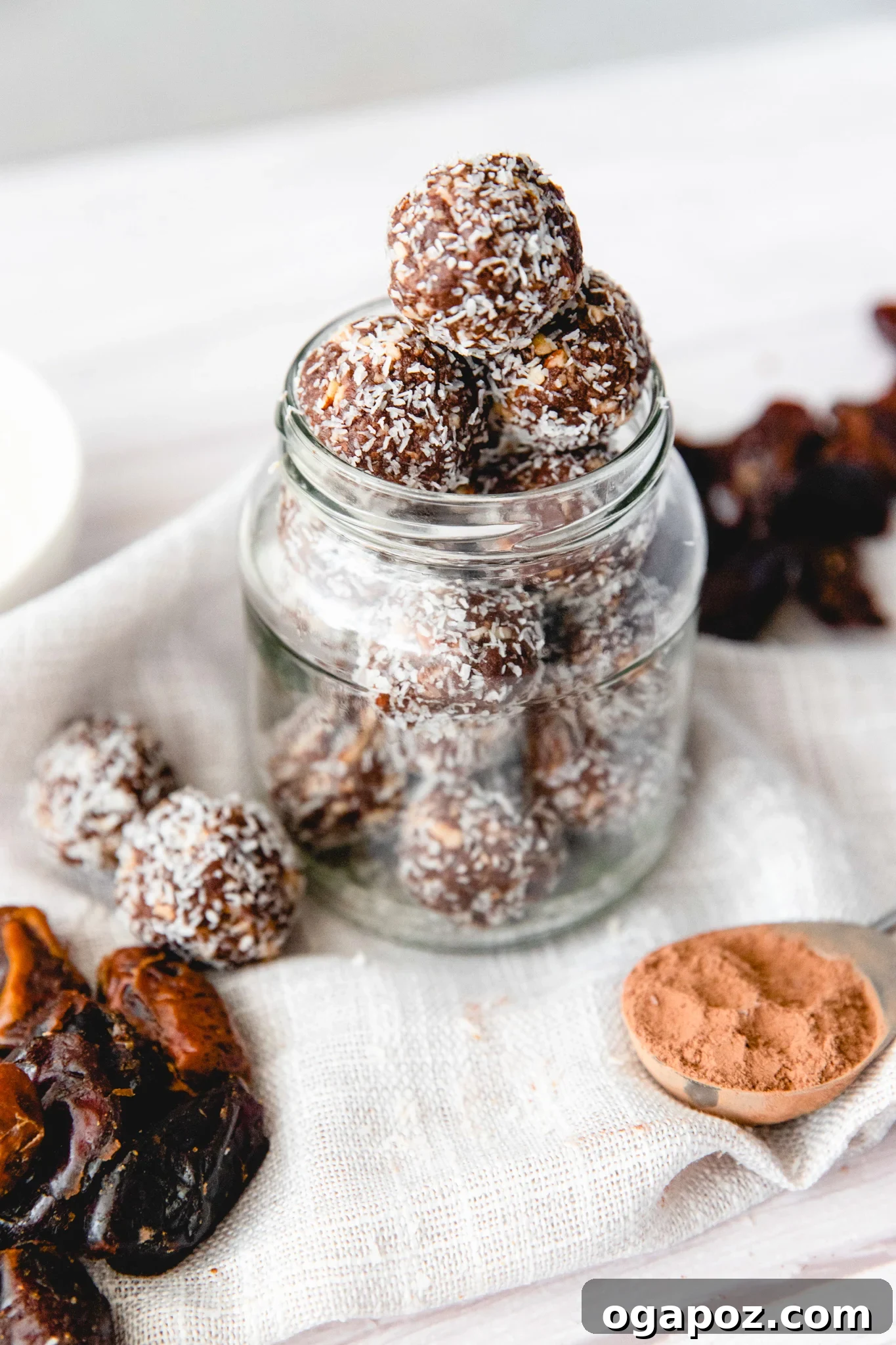 No-Bake Date Energy Bites 2 date protein balls with shredded coconut in a jar stacked on top of each other