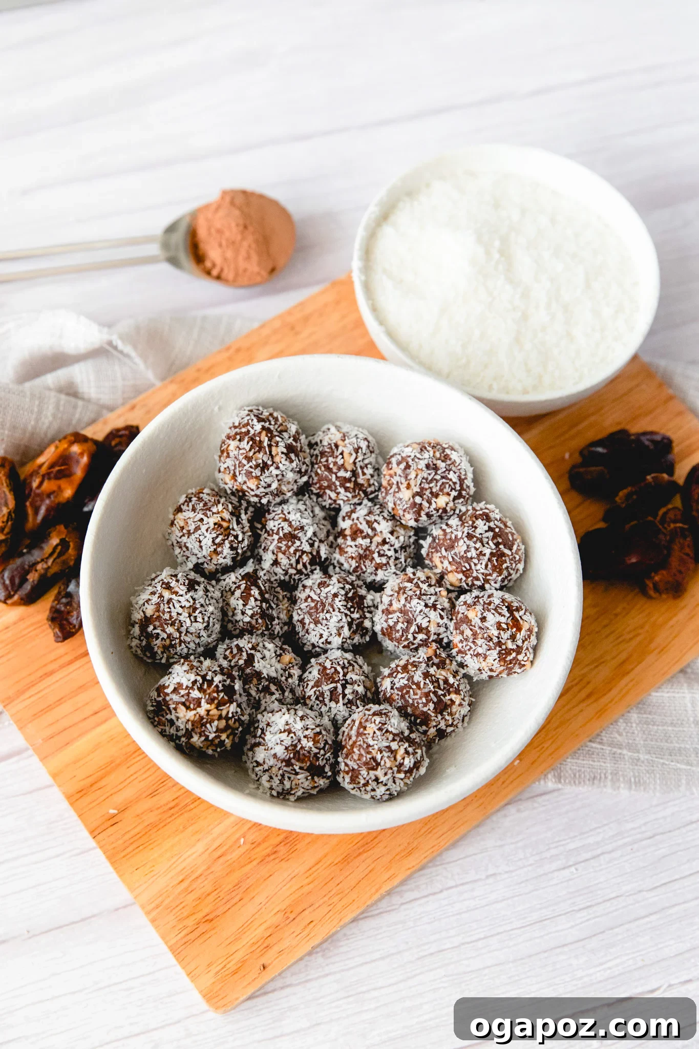 No-Bake Date Energy Bites 10 a white bowl filled with date protein balls covered in a desiccated coconut.