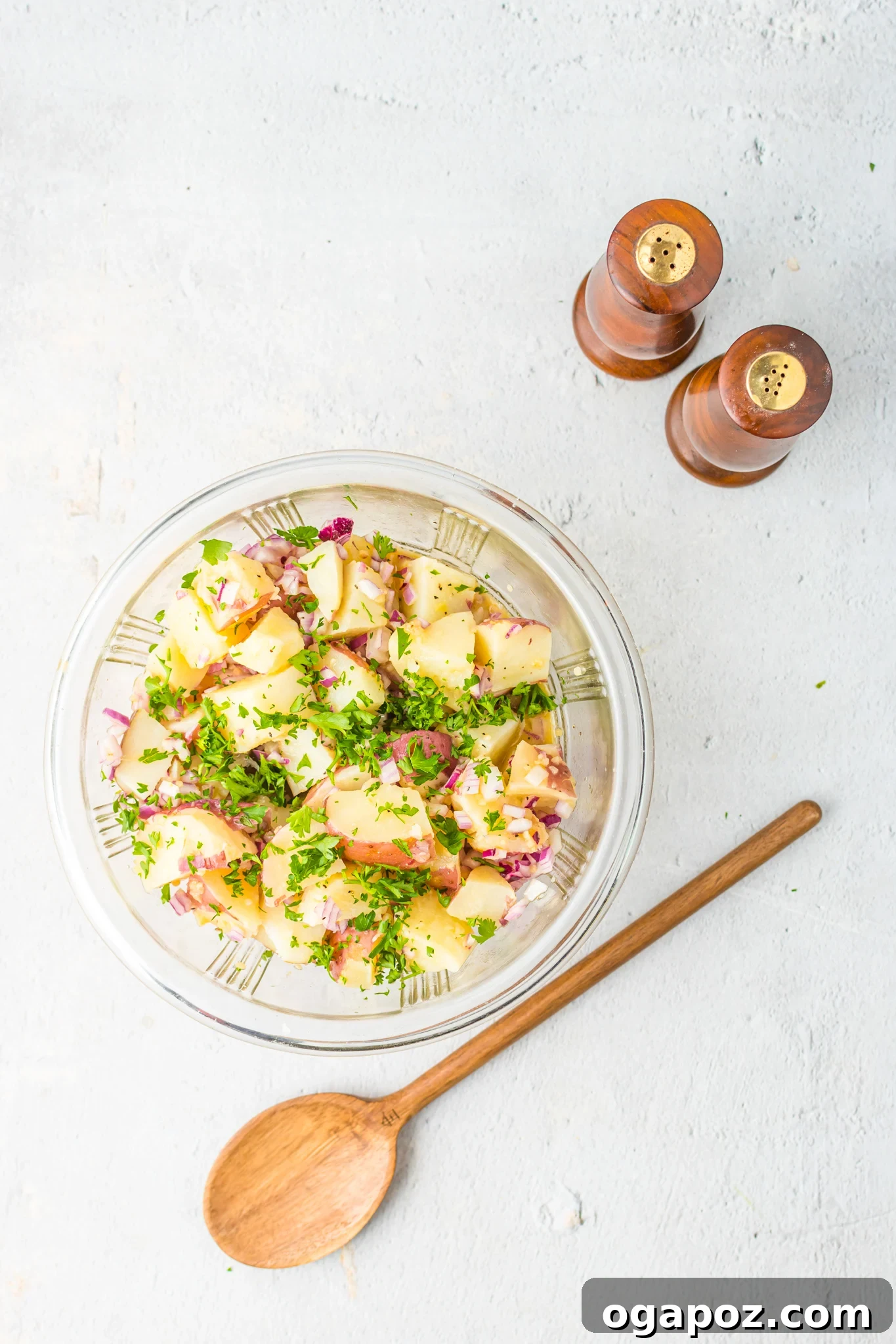 Warm German Potato Salad 6 German Potato Salad being seasoned with salt and pepper in a mixing bowl.