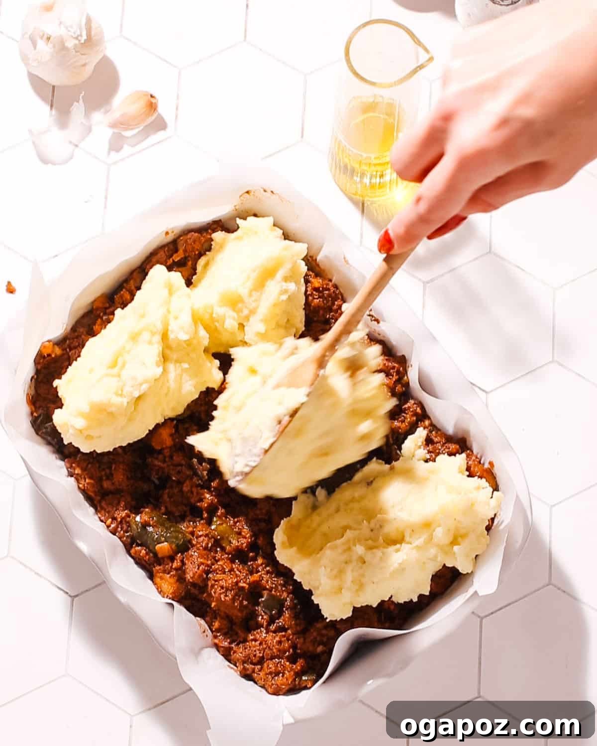 26+ Meat Sauce Masterpieces Delicious Dinners and Effortless Encore Meals 3 Greek Shepherd's Pie being topped with creamy mashed potatoes