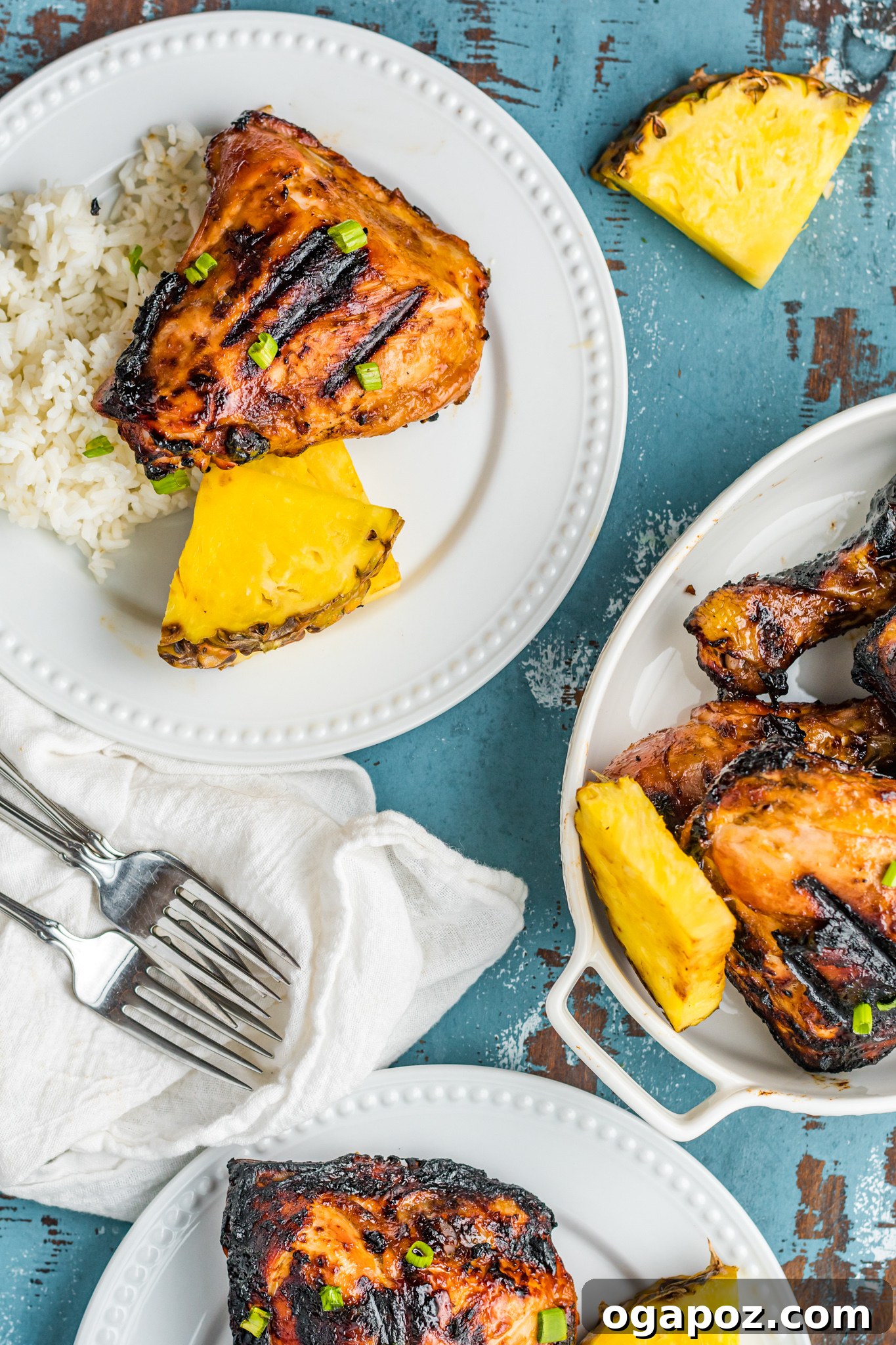 Two plates of grilled Huli Huli Chicken served with coconut rice and pineapple, ready for a tropical meal.