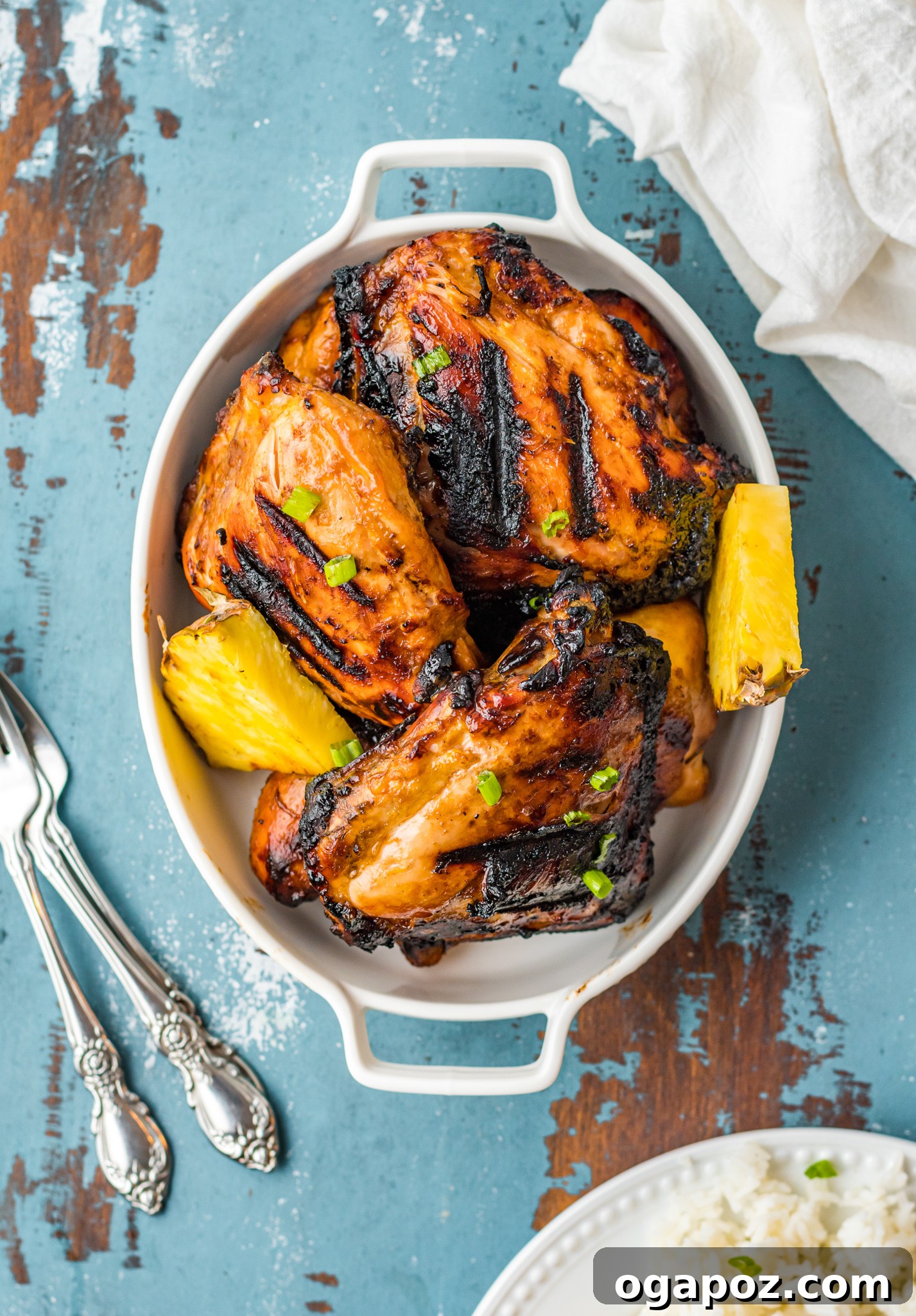 A rustic blue wooden table setting showcasing a platter of Grilled Huli Huli Chicken, emphasizing its homemade, comforting appeal.