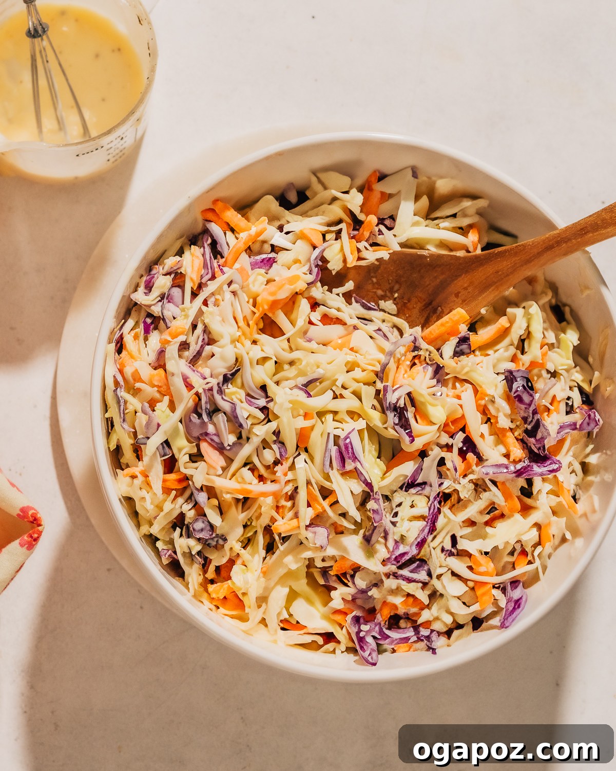 Whip Up the Easiest Creamy Coleslaw 2 Easy Coleslaw recipe in a bowl with a spoon and homemade coleslaw dressing in a glass with a whisk.