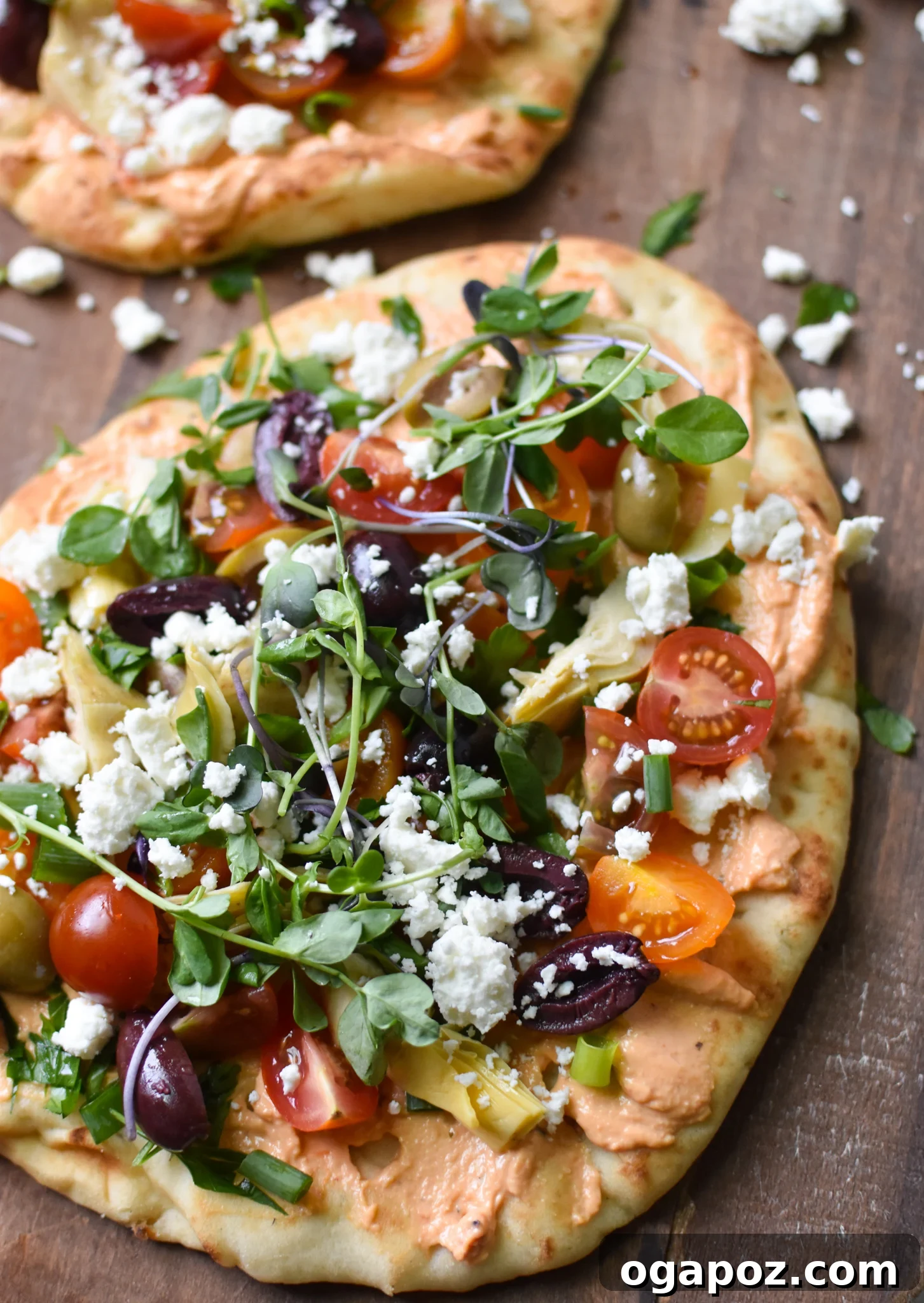 Sun-Kissed Mediterranean Naan Pizza 2 Mediterranean Naan Bread Pizza on a cutting board, garnished with fresh herbs and olive oil.