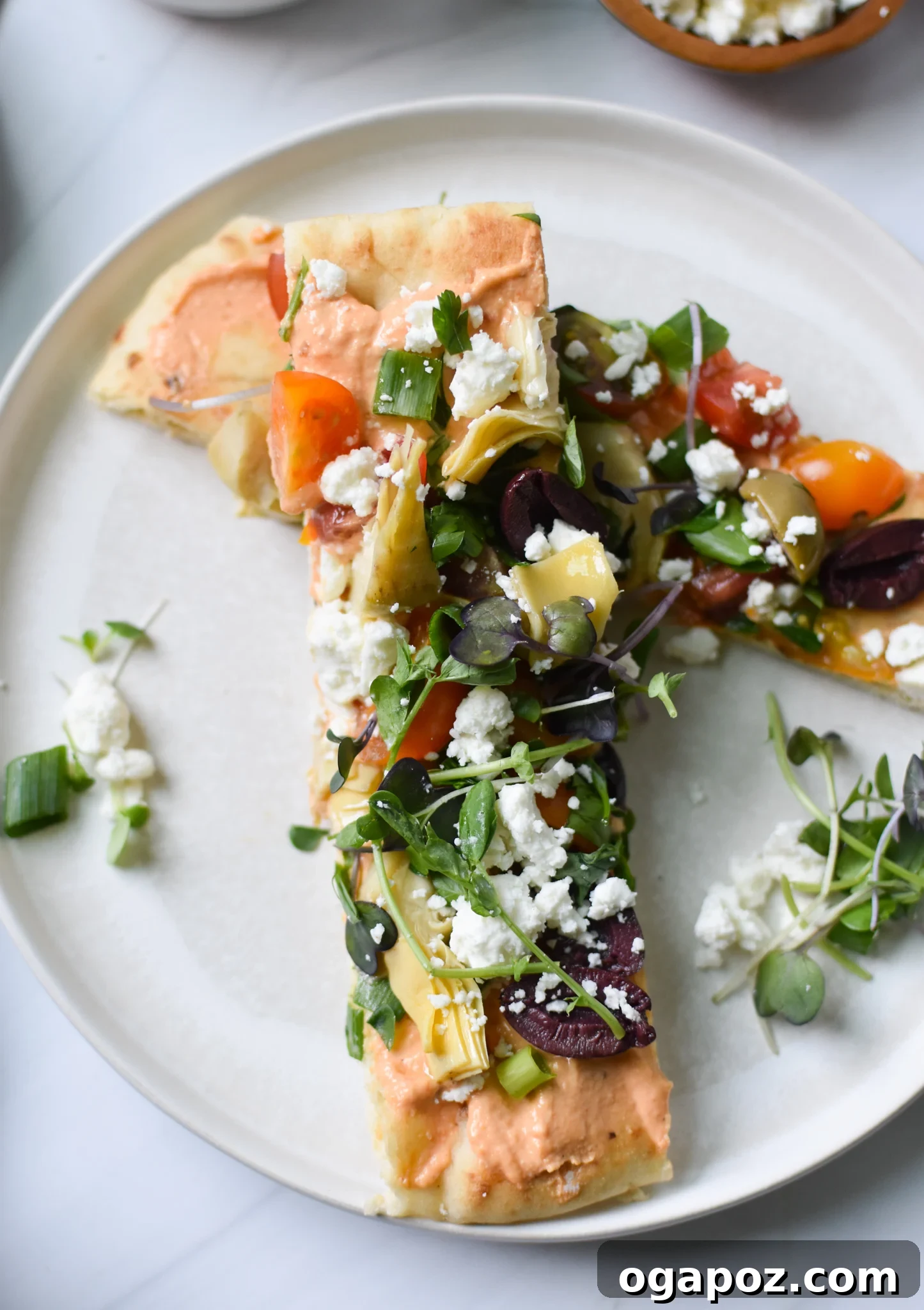 Sun-Kissed Mediterranean Naan Pizza 5 Mediterranean Naan Bread Pizza served on a plate with extra fresh herbs.