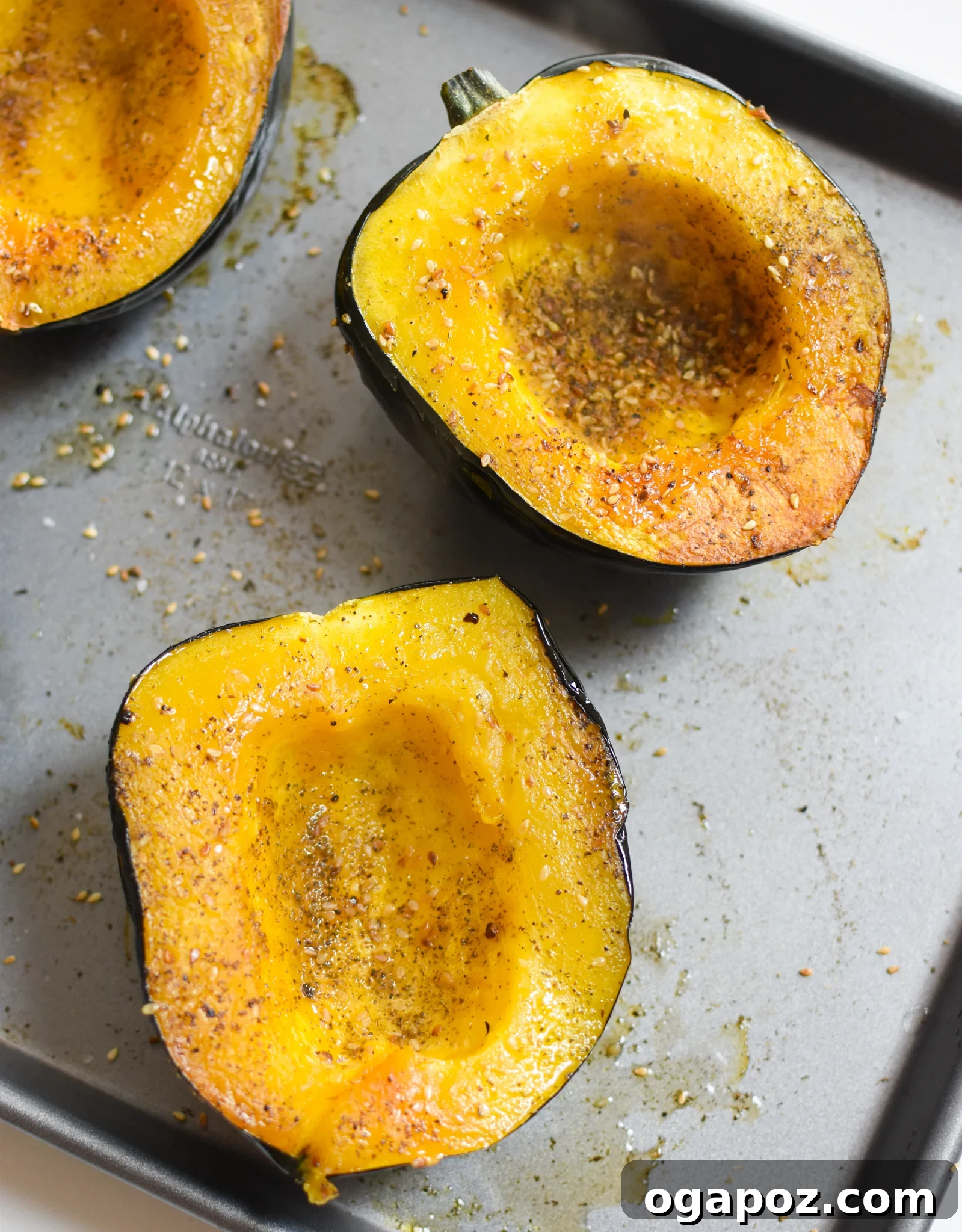 Sun-Kissed Mediterranean Stuffed Acorn Squash 8 Mediterranean Stuffed Acorn Squash halves seasoned with salt and za'atar on a baking sheet.