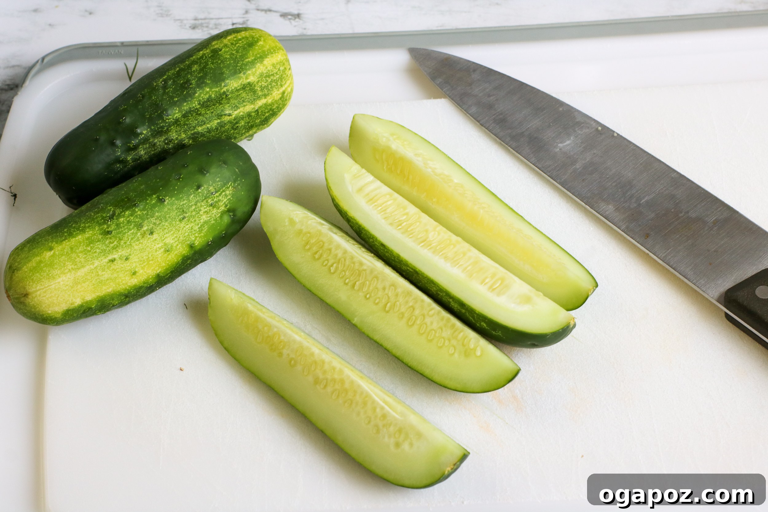 Easy No-Cook Dill Pickles 3 Fresh cucumbers, dill, and garlic on a cutting board, ready for pickling.