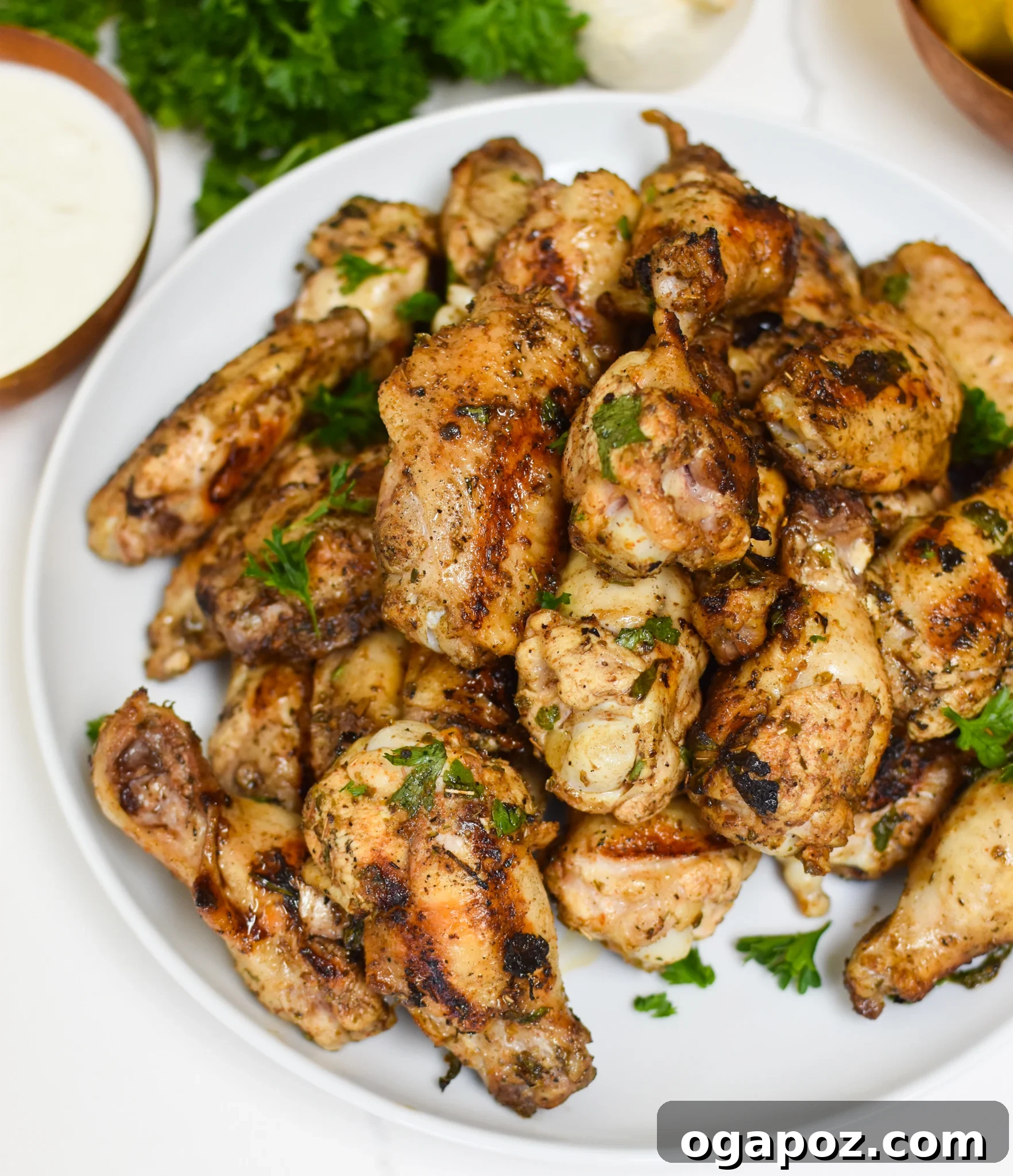 Zesty Mediterranean Grilled Wings 7 Freshly grilled Mediterranean Chicken Wings on a platter, garnished with chopped parsley.