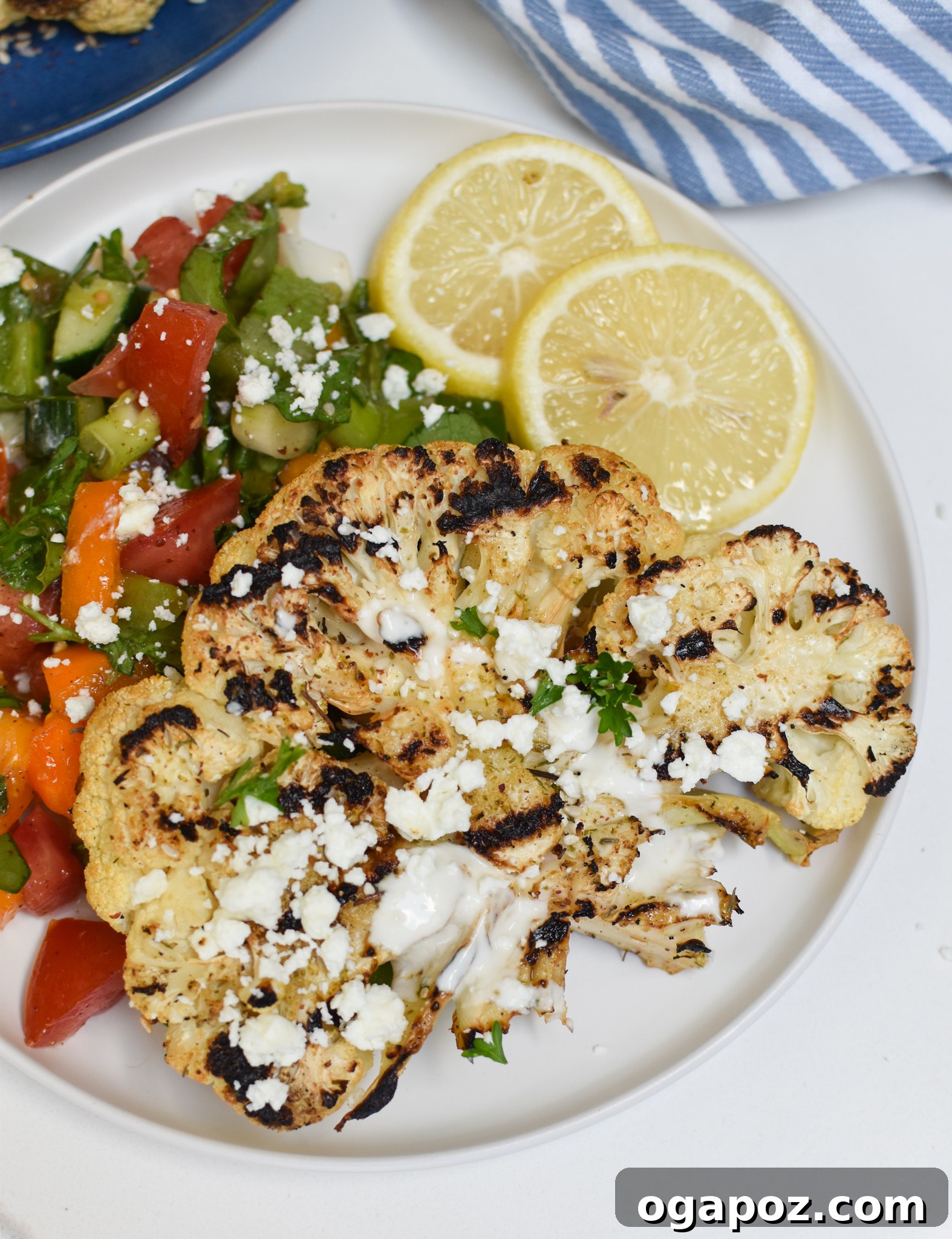 Smoky Grilled Cauliflower Steaks with Creamy Tahini Yogurt 7 Grilled Cauliflower Steaks with Yogurt Tahini Sauce served alongside a fresh green salad.