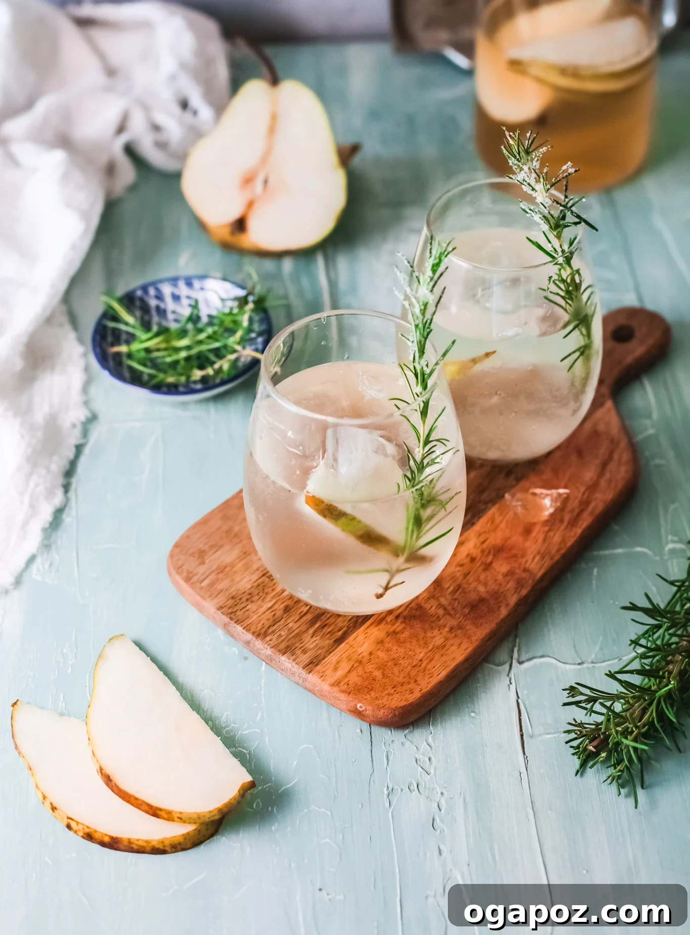 Refreshing White Sangria 2 A chilled glass of White Sangria, garnished with pear slices and a rosemary sprig, ready to be enjoyed.