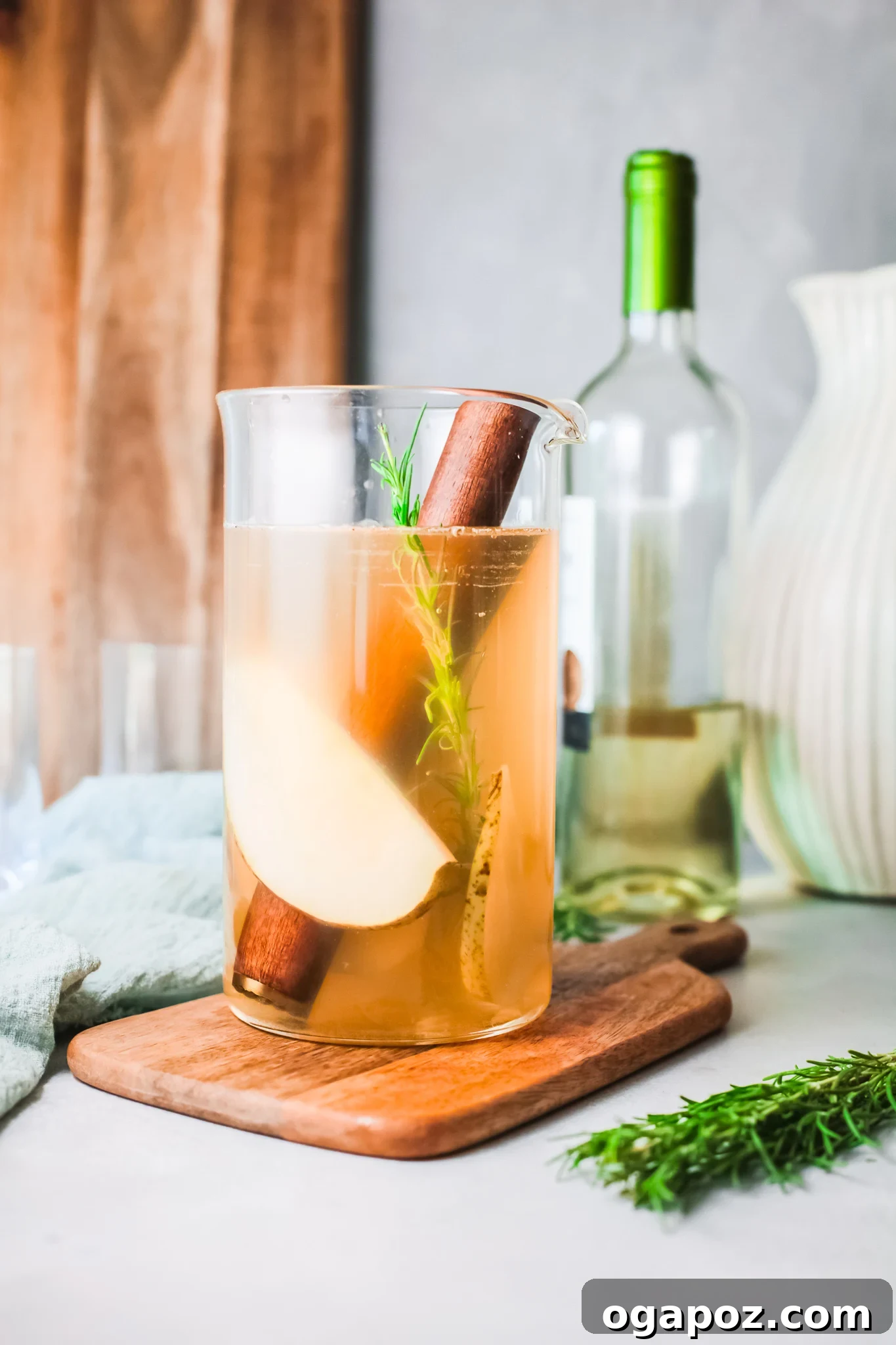 Refreshing White Sangria 4 Pouring white wine into a pitcher with sliced pears and rosemary for White Sangria.