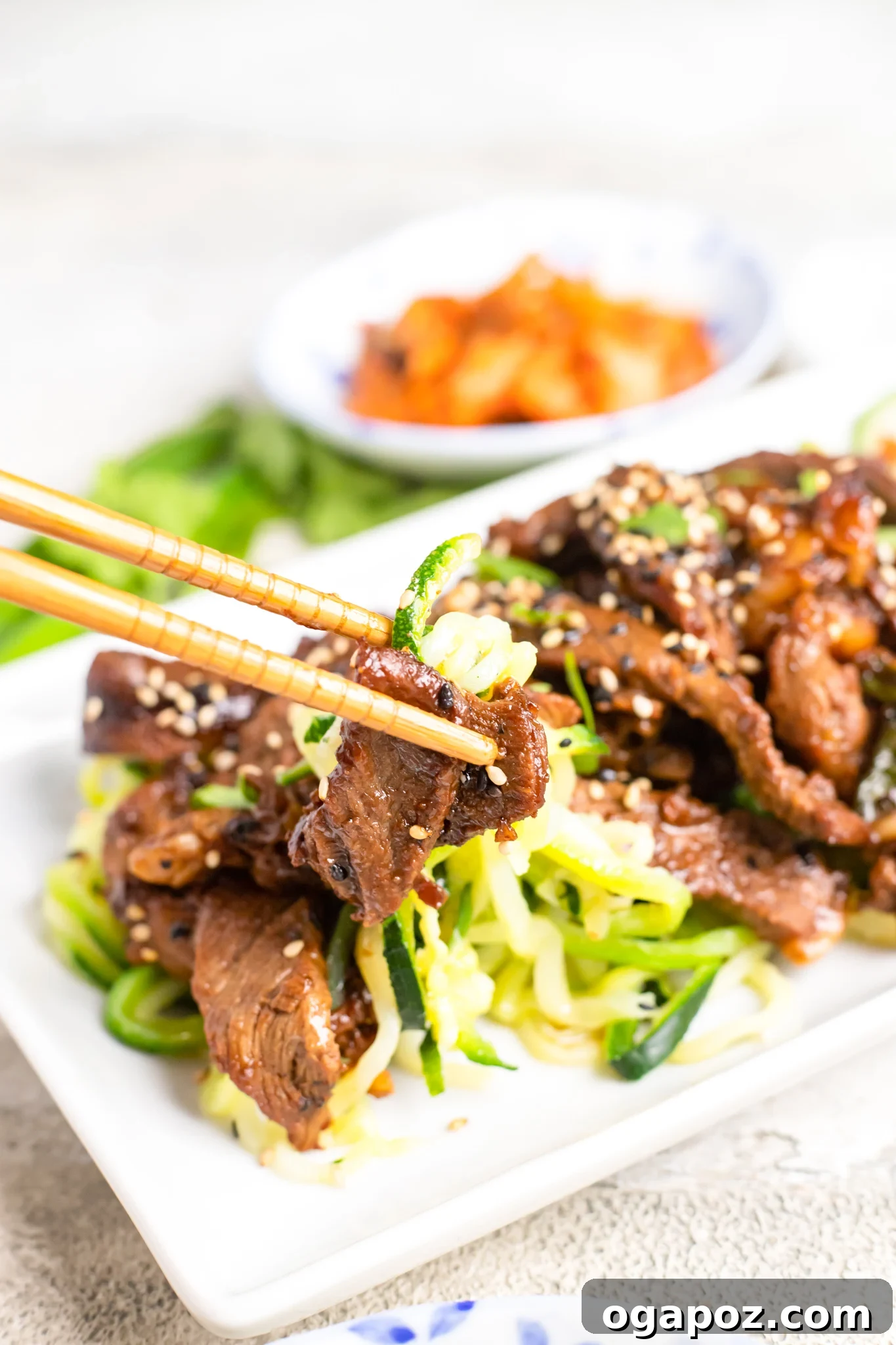 Savory Bulgogi Zucchini Ribbons 9 A bowl of Beef Bulgogi with Zucchini Noodles, garnished with green onions and sesame seeds, ready to be served with chopsticks.