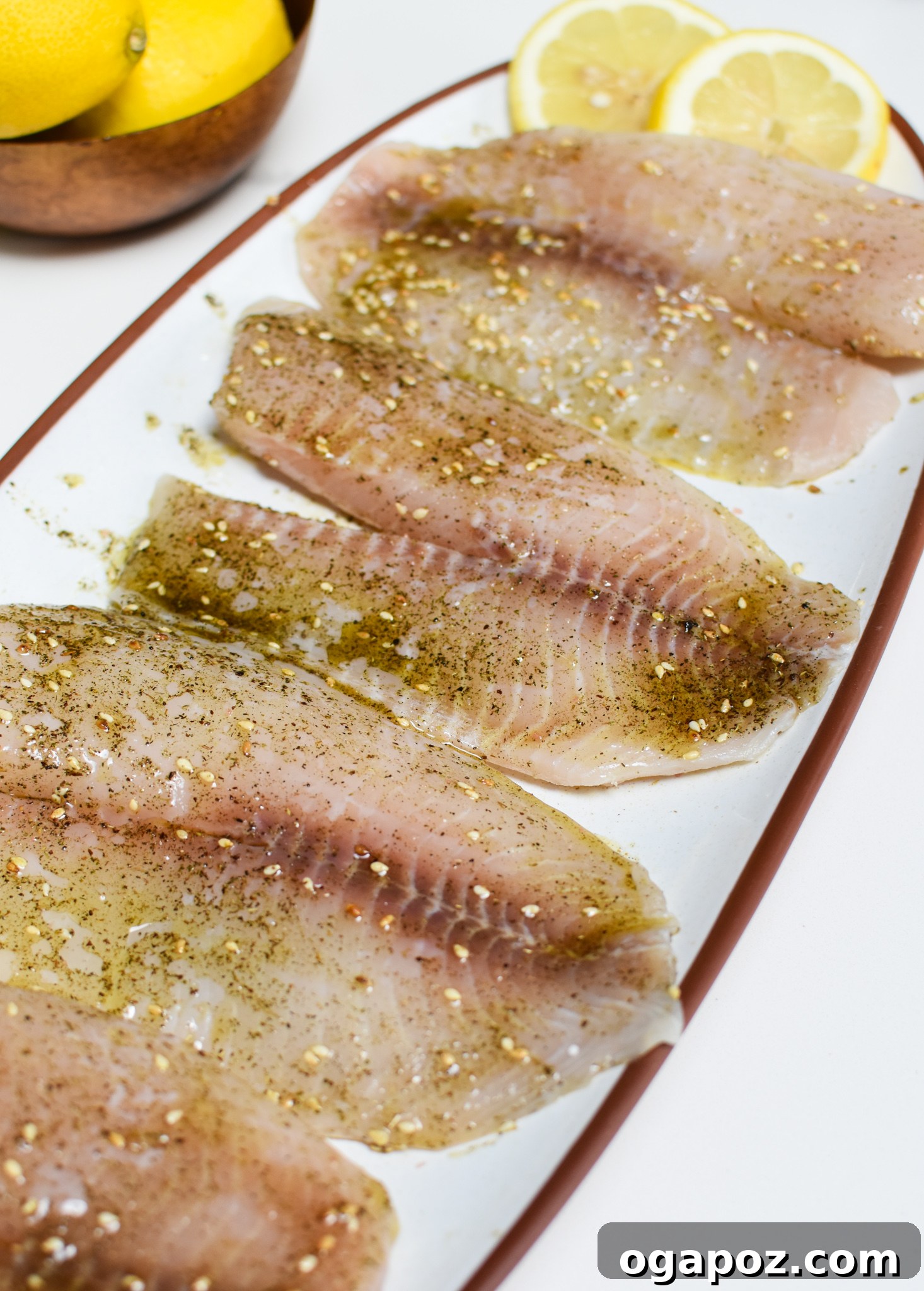 Effortless Mediterranean Baked Tilapia 6 Mediterranean Baked Tilapia on a serving platter with lemon slices.