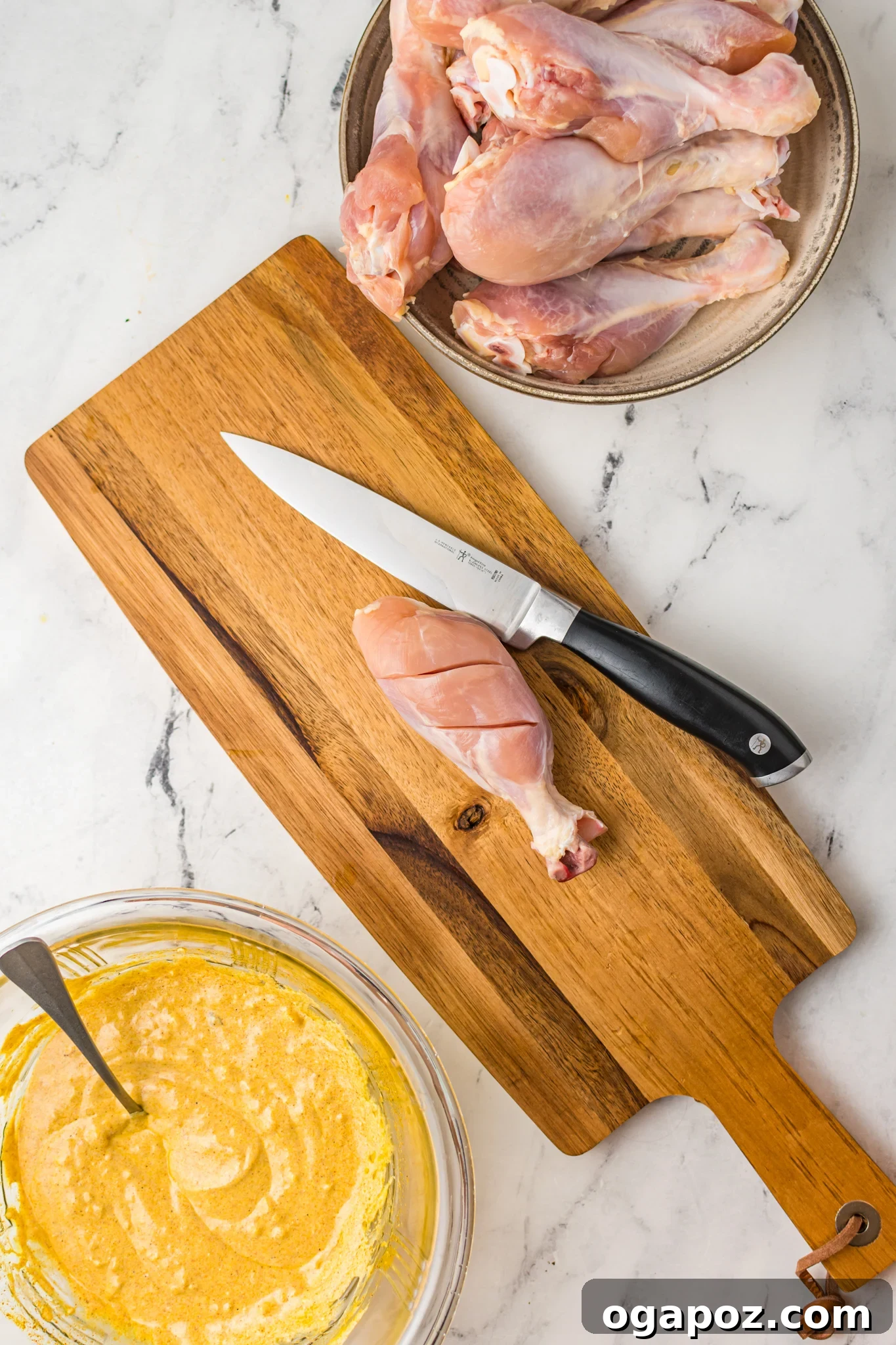 Crispy Air Fryer Tandoori Chicken Drumsticks 5 Raw chicken legs on a wooden cutting board with two or three deep slices expertly cut into the thickest part of each drumstick to enhance marinade penetration.