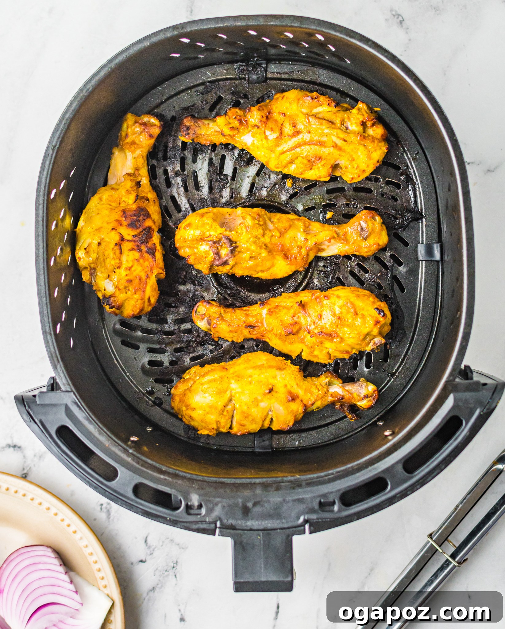 Crispy Air Fryer Tandoori Chicken Drumsticks 8 Air Fryer Tandoori Chicken Legs cooking in the air fryer basket, showing a beautiful golden-brown color and slight char, indicating they are nearing completion.