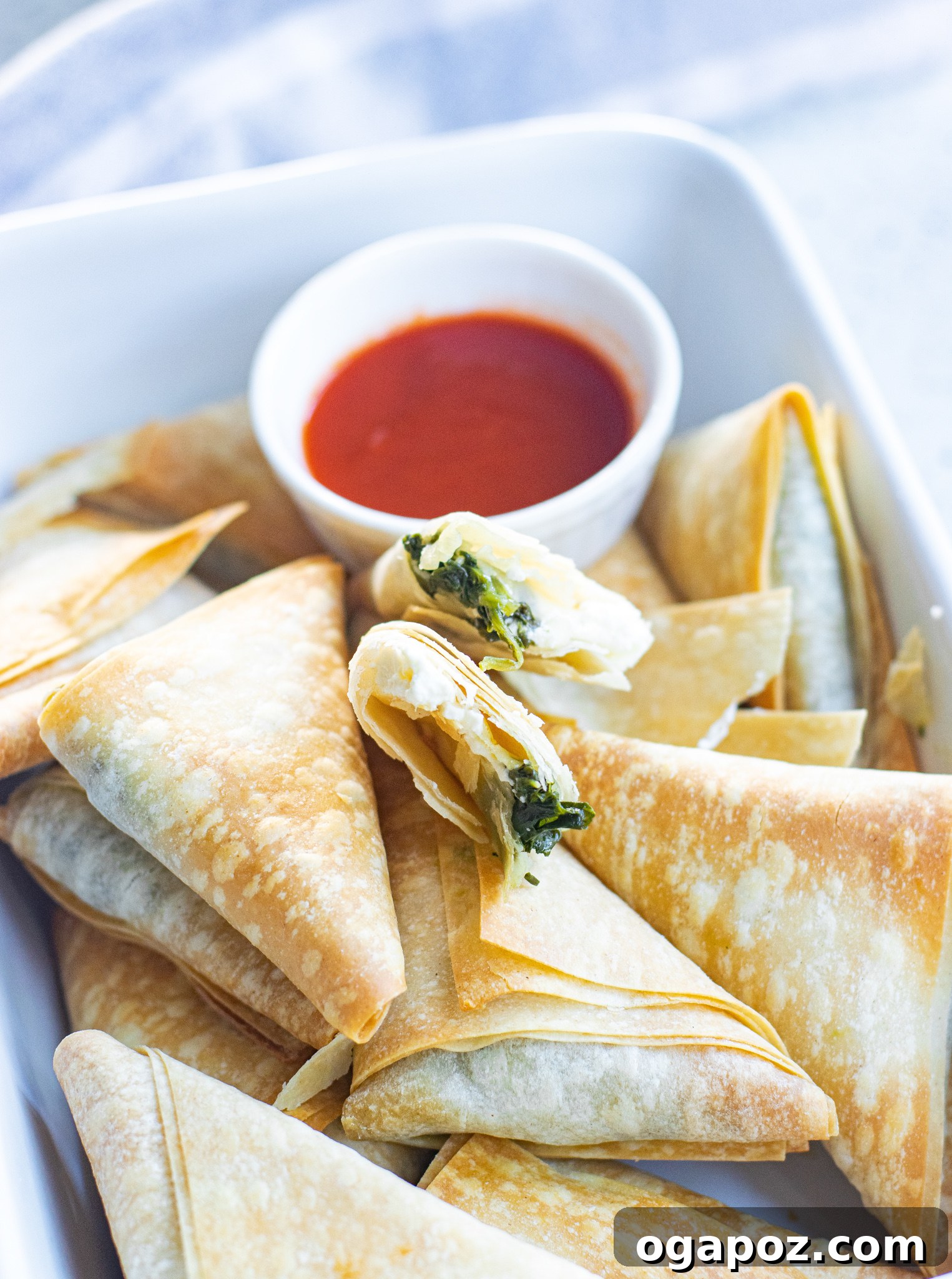 Savory Spinach and Feta Phyllo Pastries 3 Prepared Spanakopita Triangles arranged in a white baking dish.