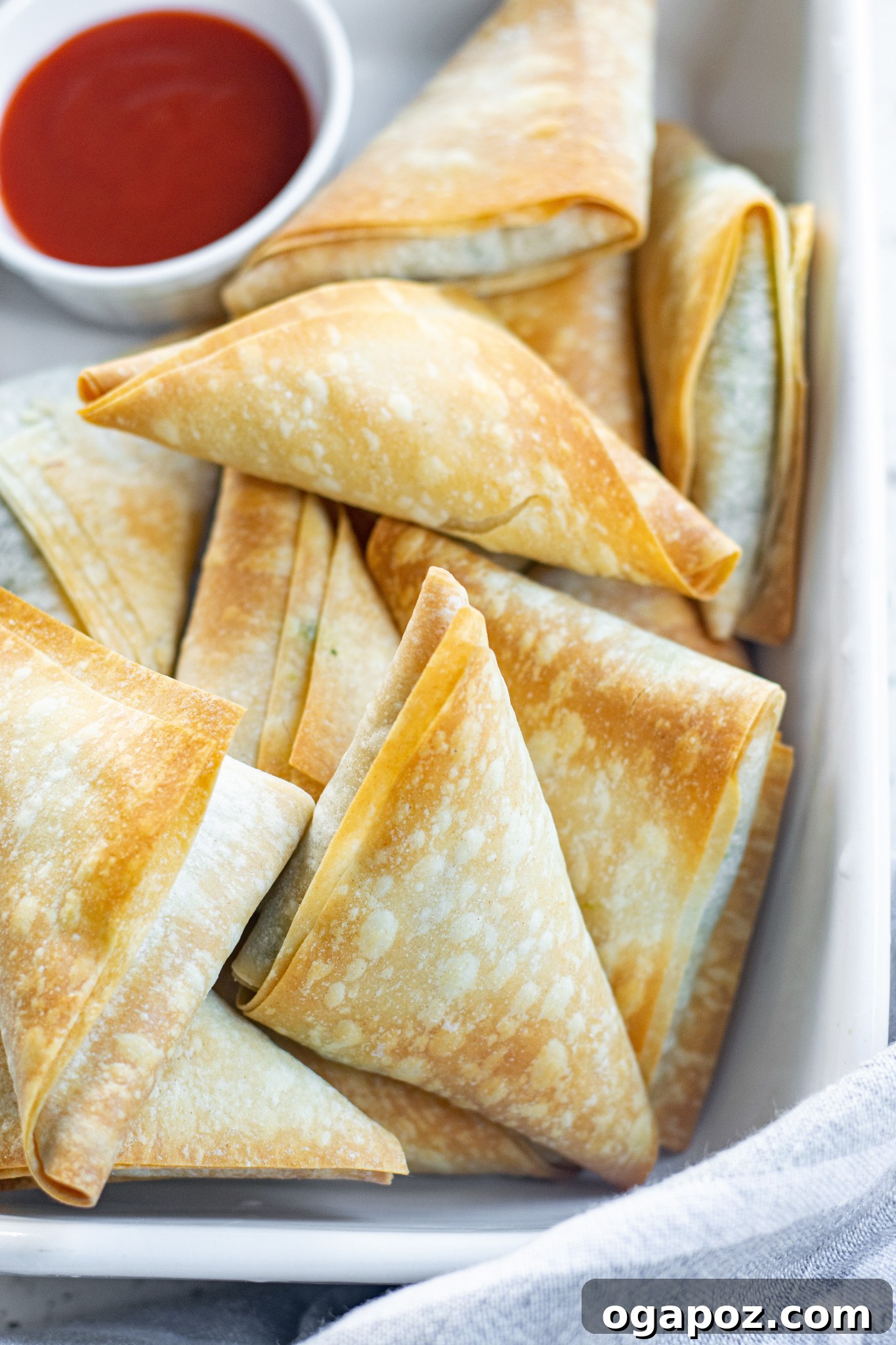 Savory Spinach and Feta Phyllo Pastries 4 Close-up of baked Spanakopita Triangles with a side of red dipping sauce.