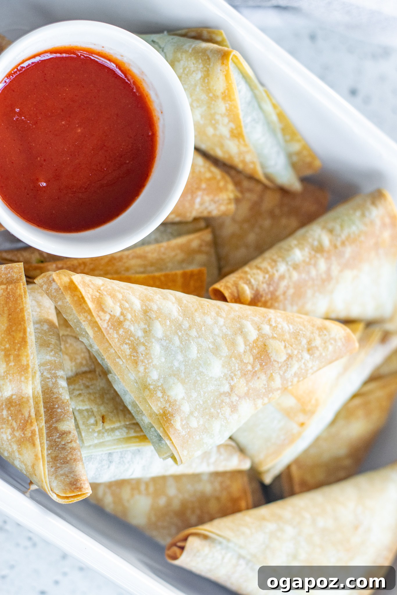 Savory Spinach and Feta Phyllo Pastries 9 Freshly baked Spanakopita Triangles in a white baking pan.