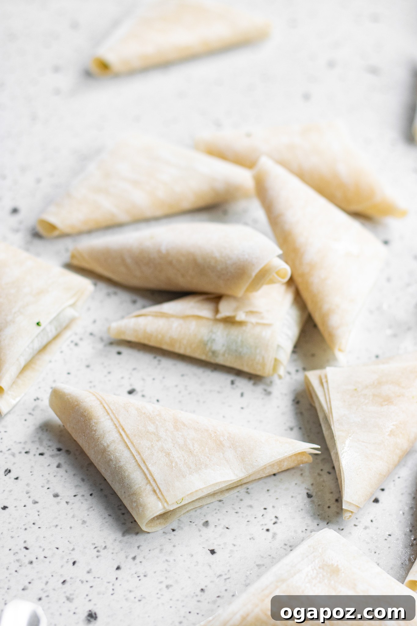 Savory Spinach and Feta Phyllo Pastries 10 Assortment of Spanakopita Triangles elegantly arranged on a white platter.