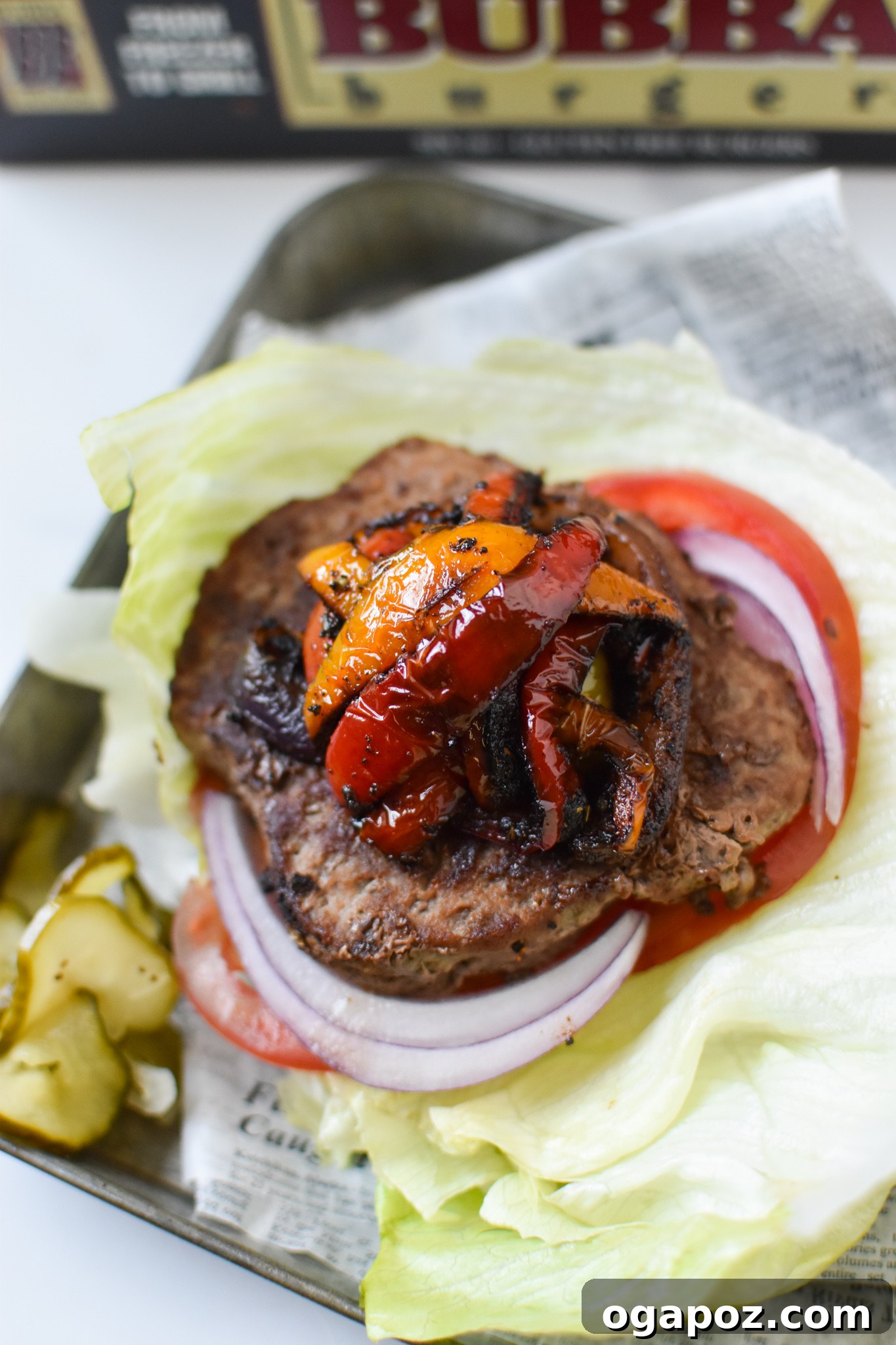 Fiesta Lettuce Burger 2 A beautifully assembled Fajita Lettuce Burger, showcasing a juicy BUBBA angus patty, colorful bell peppers, and onions, served on a crisp lettuce wrap on a rustic metal plate.