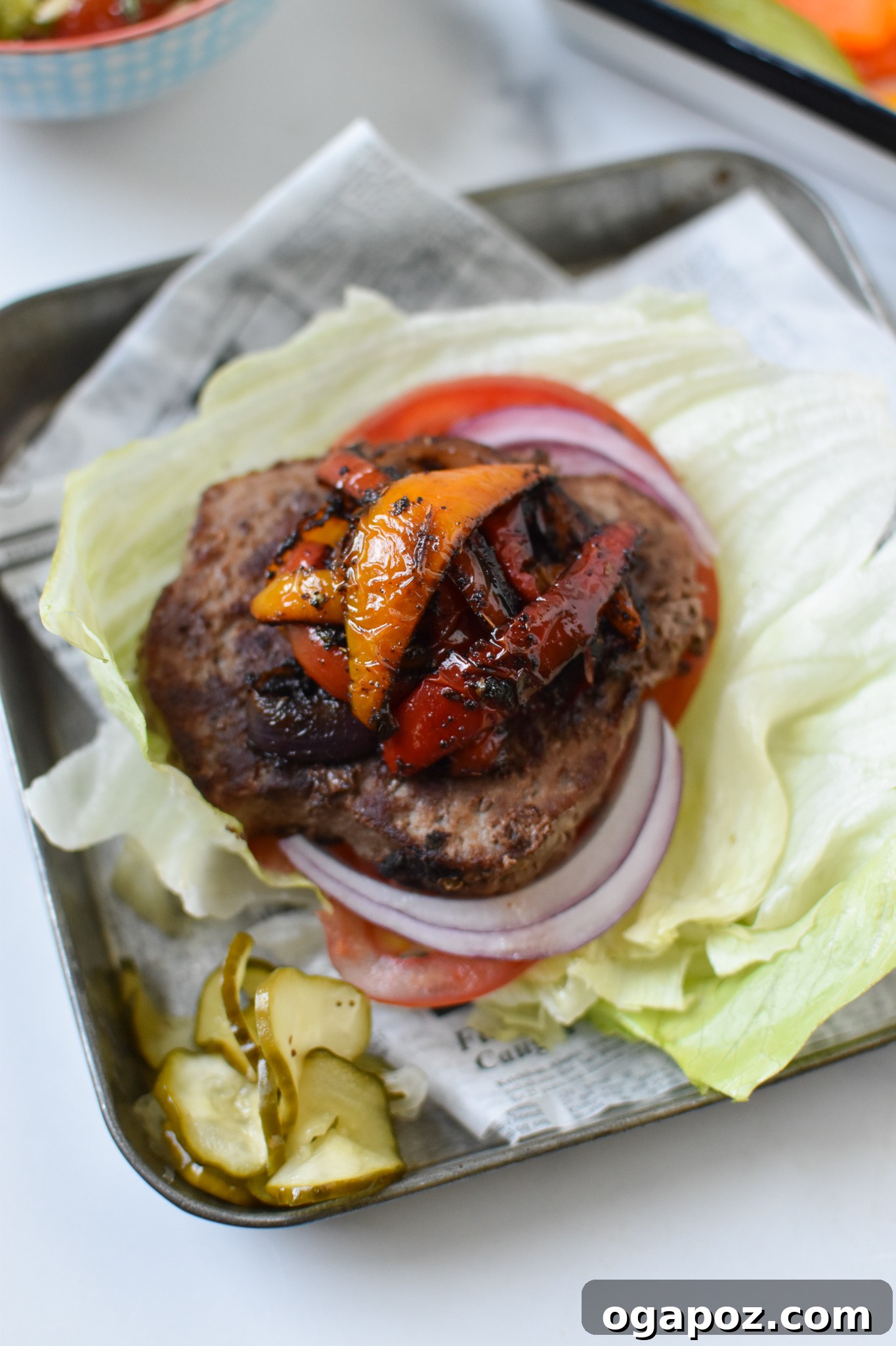 Fiesta Lettuce Burger 4 Close-up of Fajita Lettuce Burger with vibrant bell peppers and onions piled high on a juicy patty, all on a lettuce wrap.