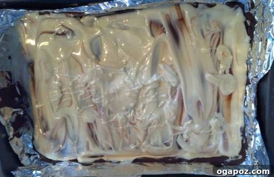 Melted white chocolate being carefully spread over the perfectly set dark chocolate base