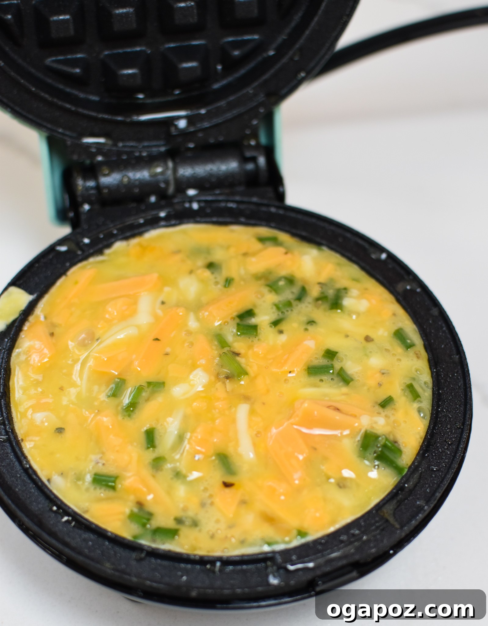 Quick and Easy Chaffles 7 A Chaffle cooking in a waffle maker, showing the golden brown texture forming.