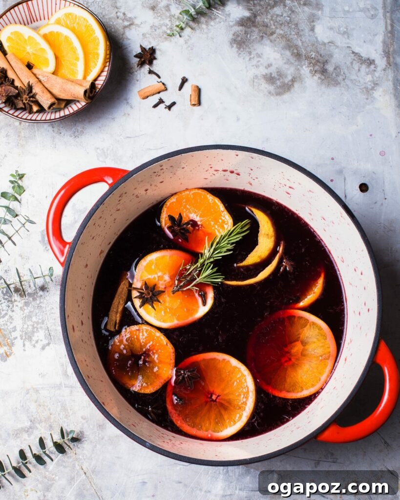 Warm & Festive: 20+ Easy Hot Drinks for a Perfect Christmas 2 Spiced Citrus Mulled Wine Recipe in a pot with orange slices and rosemary.