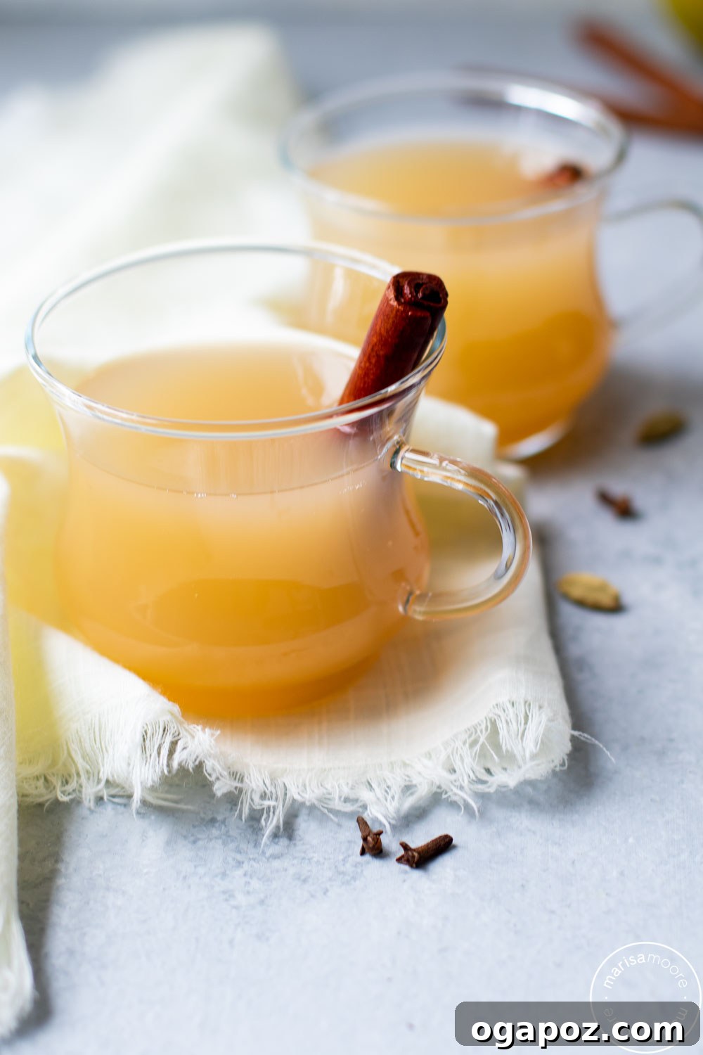 Warm & Festive: 20+ Easy Hot Drinks for a Perfect Christmas 12 Instant Pot Pear Cider in a glass, garnished with pear slices and a cinnamon stick.