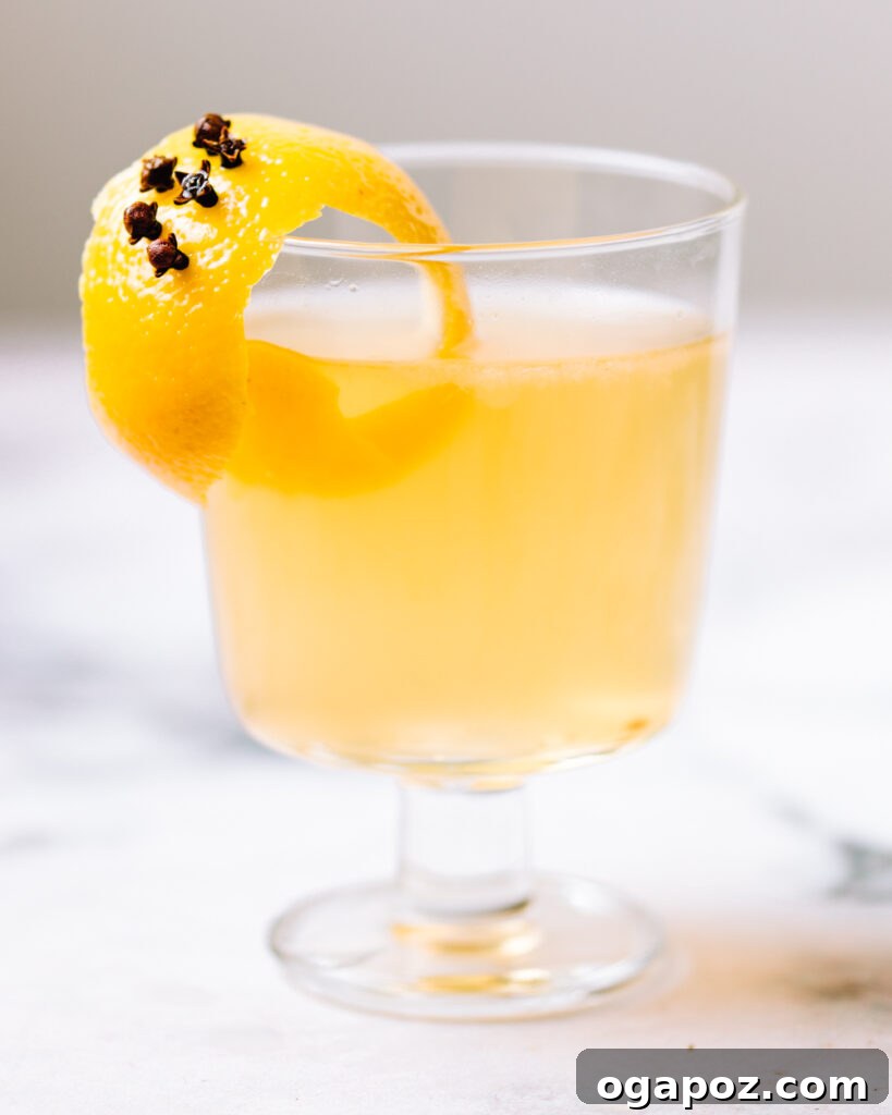 Warm & Festive: 20+ Easy Hot Drinks for a Perfect Christmas 18 Hot Toddy recipe in a glass garnished with lemon peel and cloves.