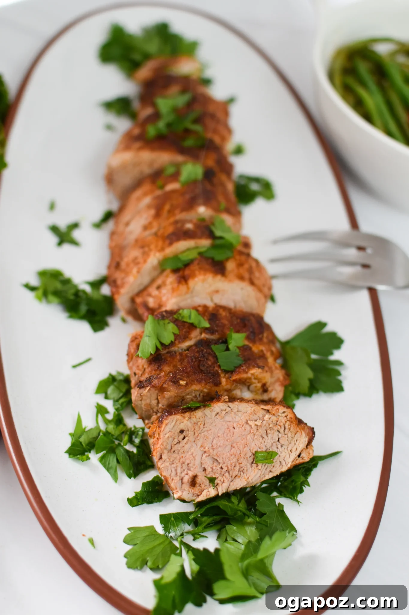 Golden Air Fryer Pork Tenderloin 4 Slices of Air Fryer Pork Tenderloin arranged beautifully on a white platter, showcasing its juicy interior and crispy crust.