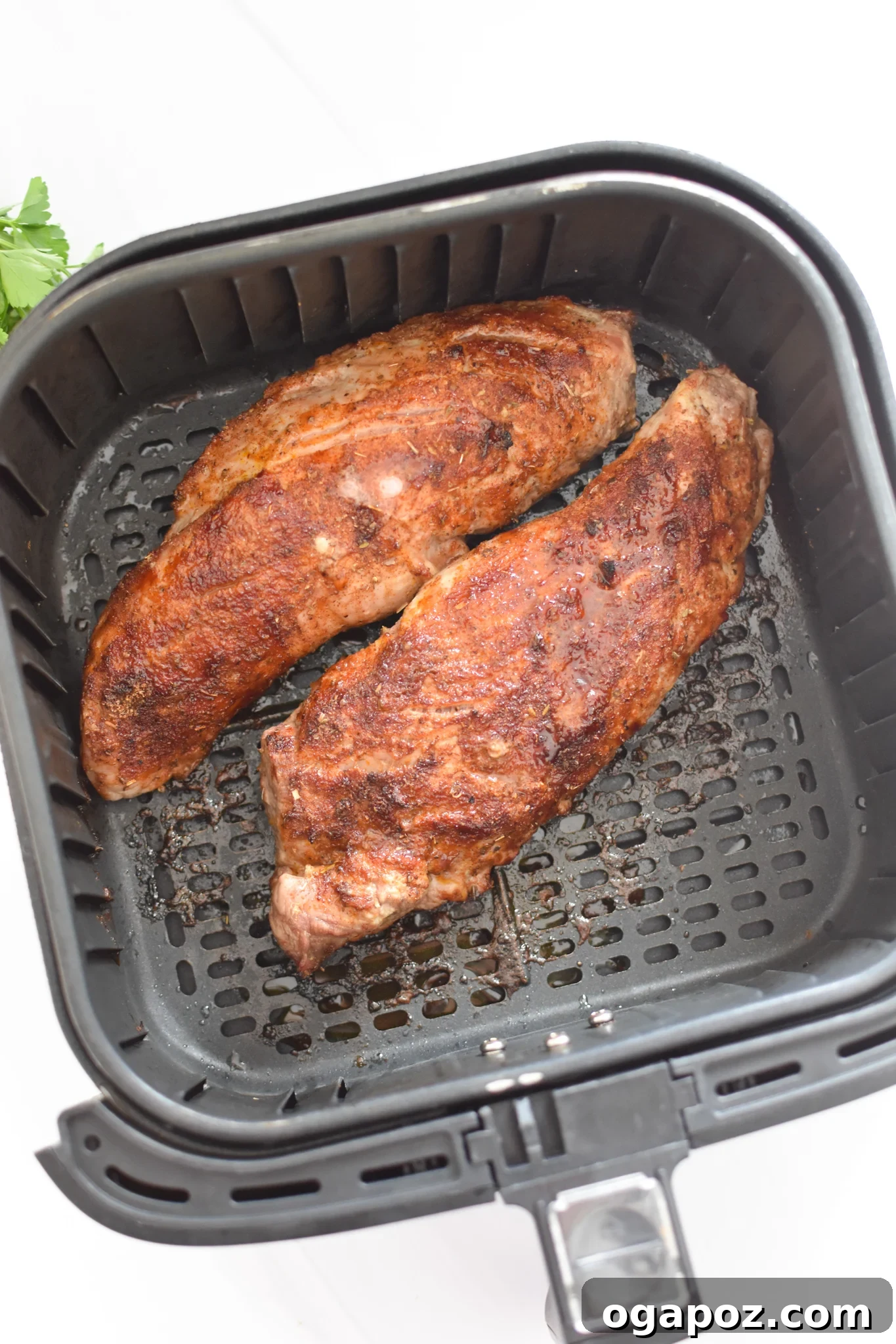Golden Air Fryer Pork Tenderloin 6 Pork tenderloin cooking in the air fryer basket, showing its crispy, browned exterior.