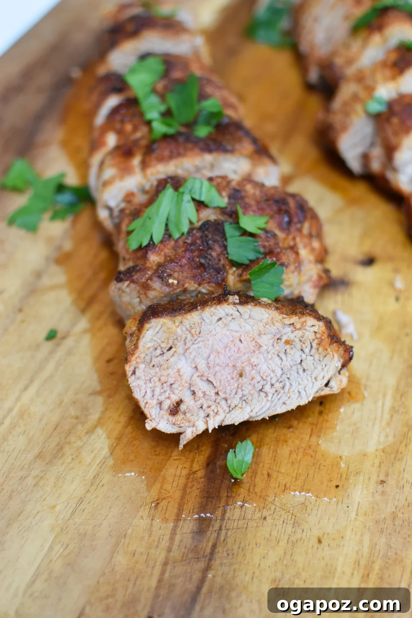 Golden Air Fryer Pork Tenderloin 7 Slices of Air Fryer Pork Tenderloin on a cutting board, garnished with fresh herbs, ready to be served.